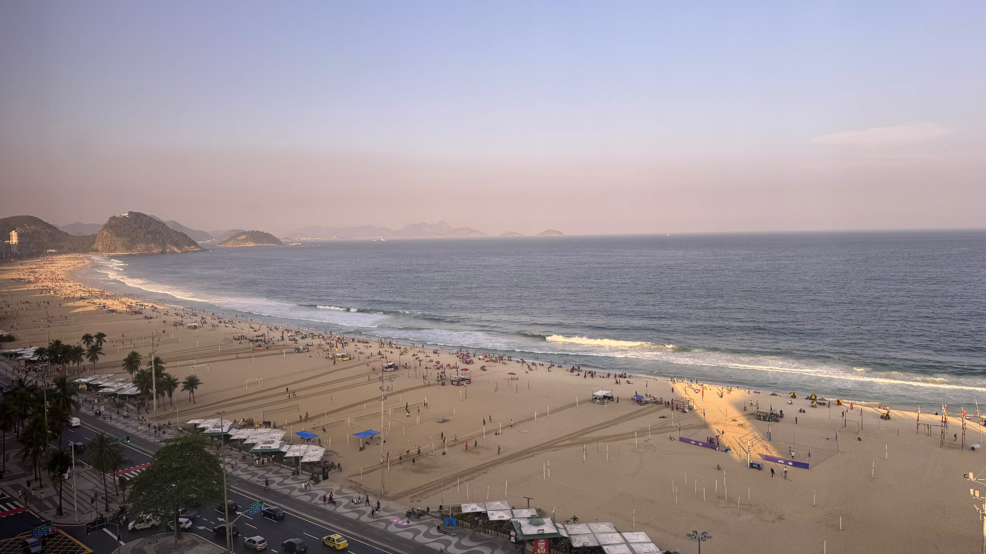 Wide elevated view along busy Copacabana Beach in late afternoon