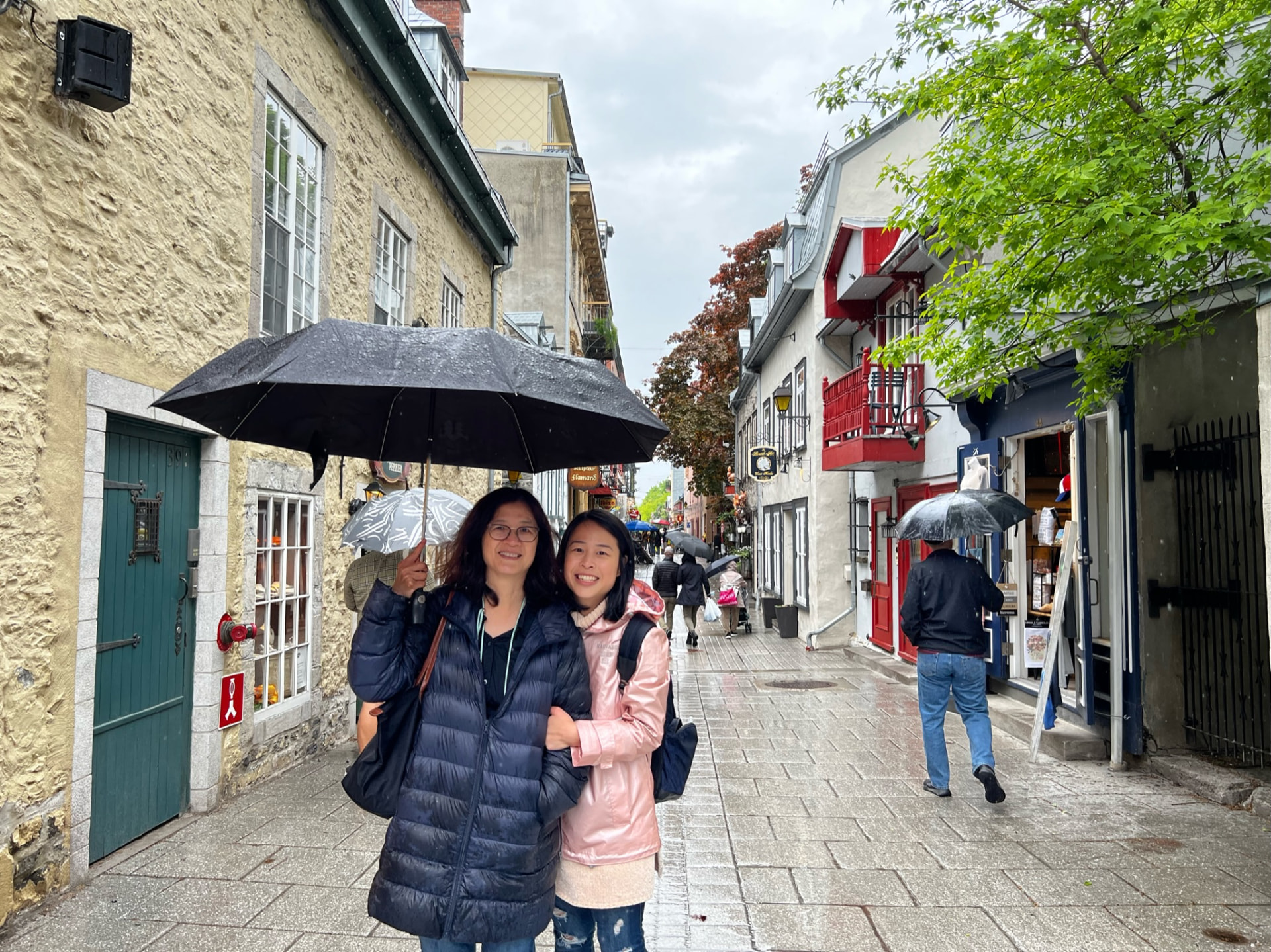 Two women under an umbrella on a rain-soaked Québec City street