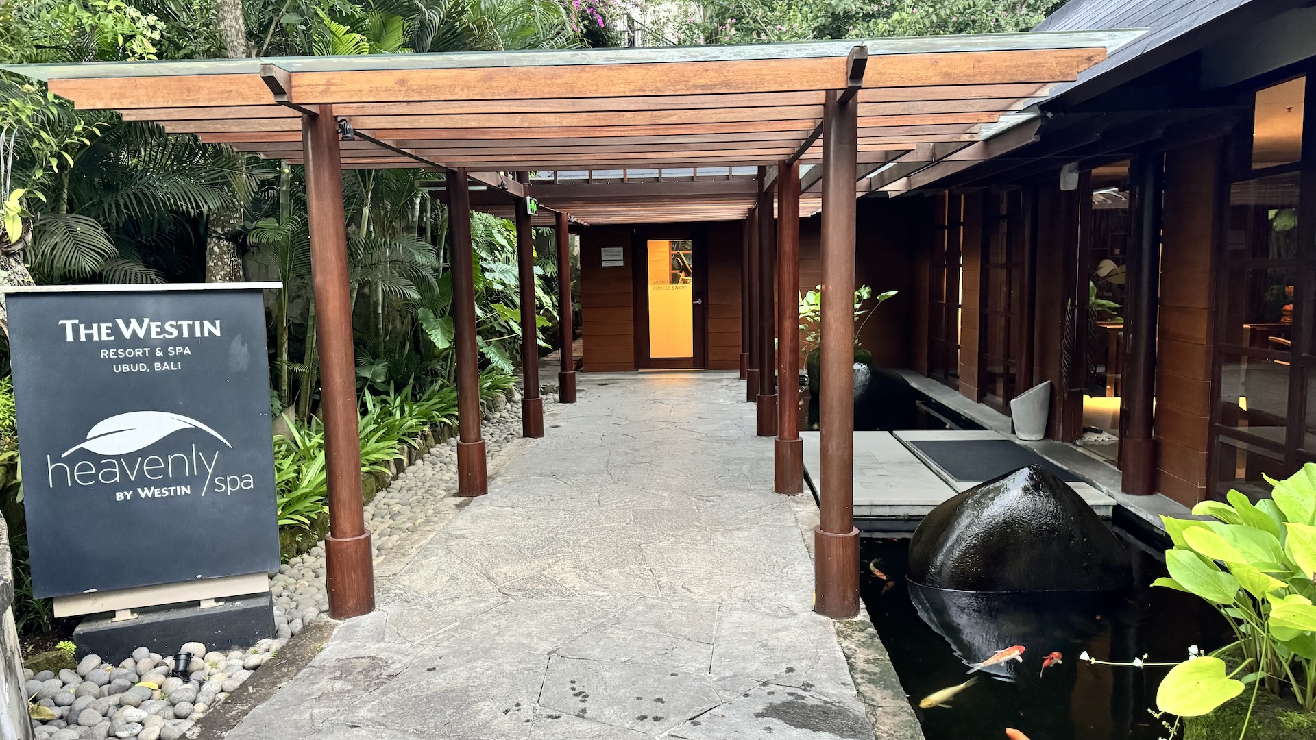 Timber walkway to the Heavenly Spa entrance beside a koi pond and tropical planting