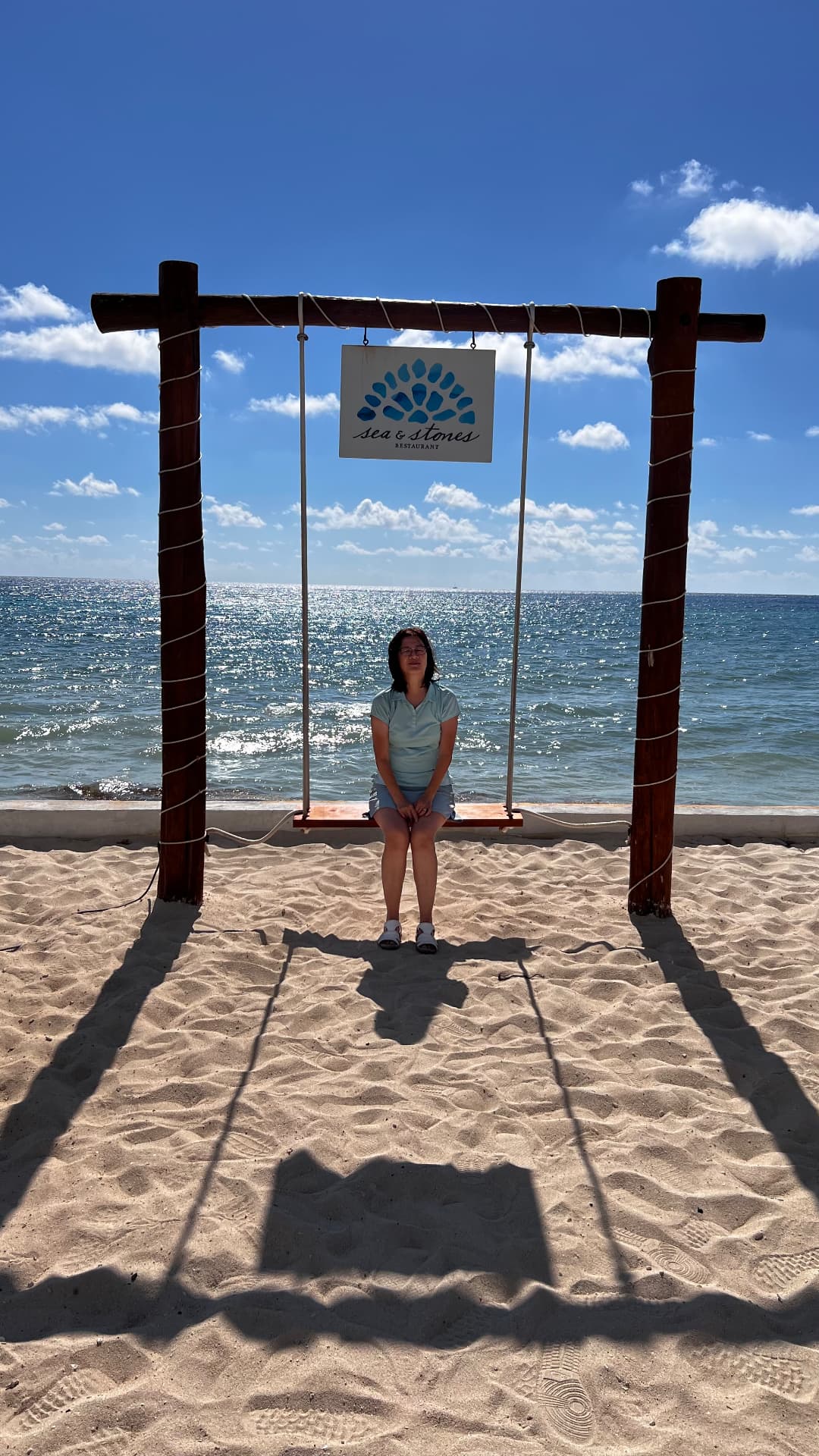 Becky sitting on an oceanfront swing at Sea and Stones
