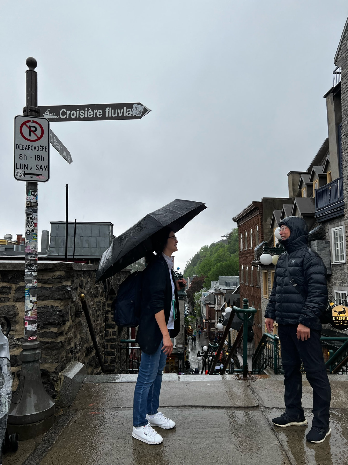 Two family members recreating a Korean drama scene in the rain above Petit Champlain