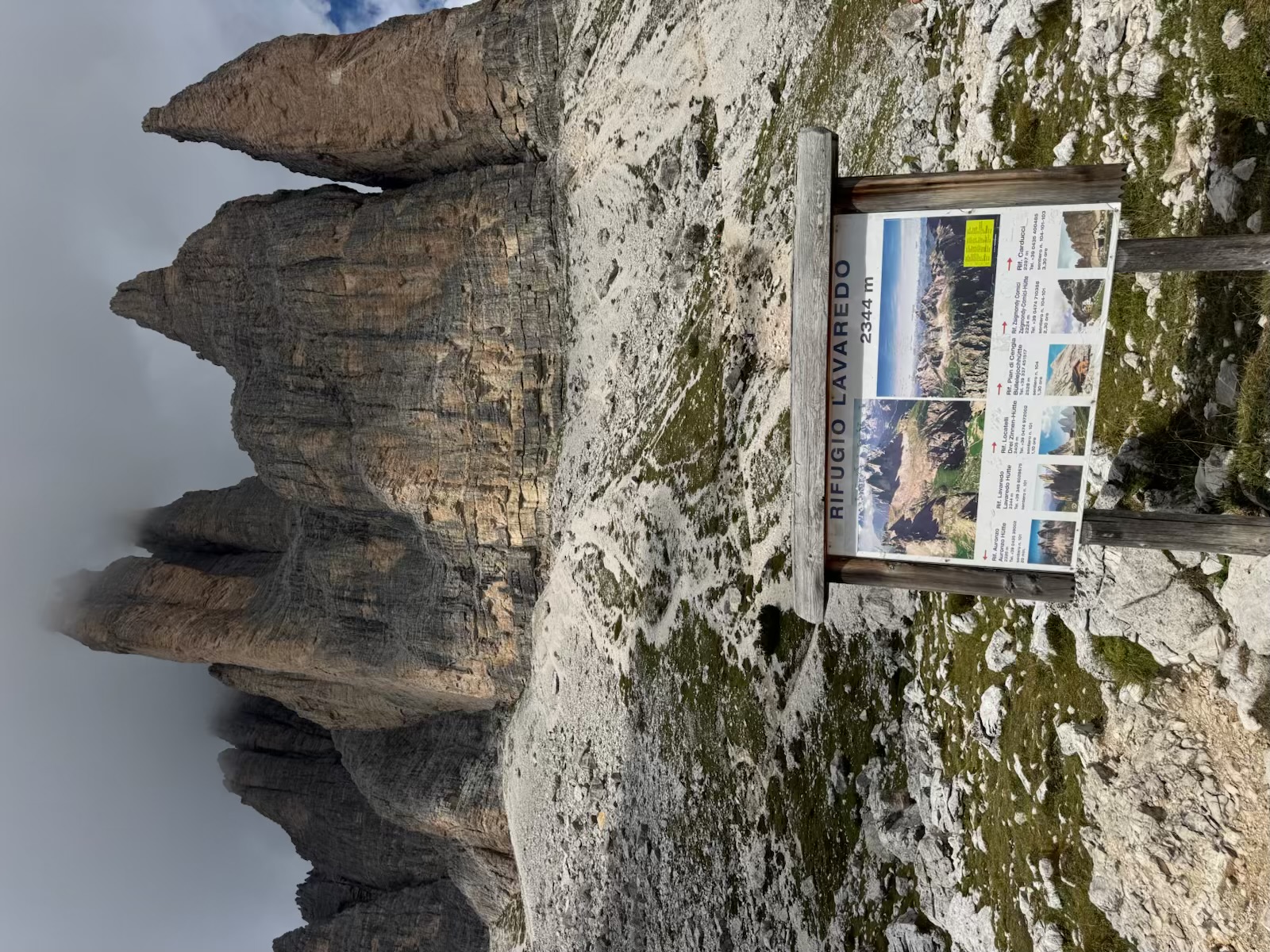 Rifugio Lavaredo sign beneath immense mist-covered limestone towers