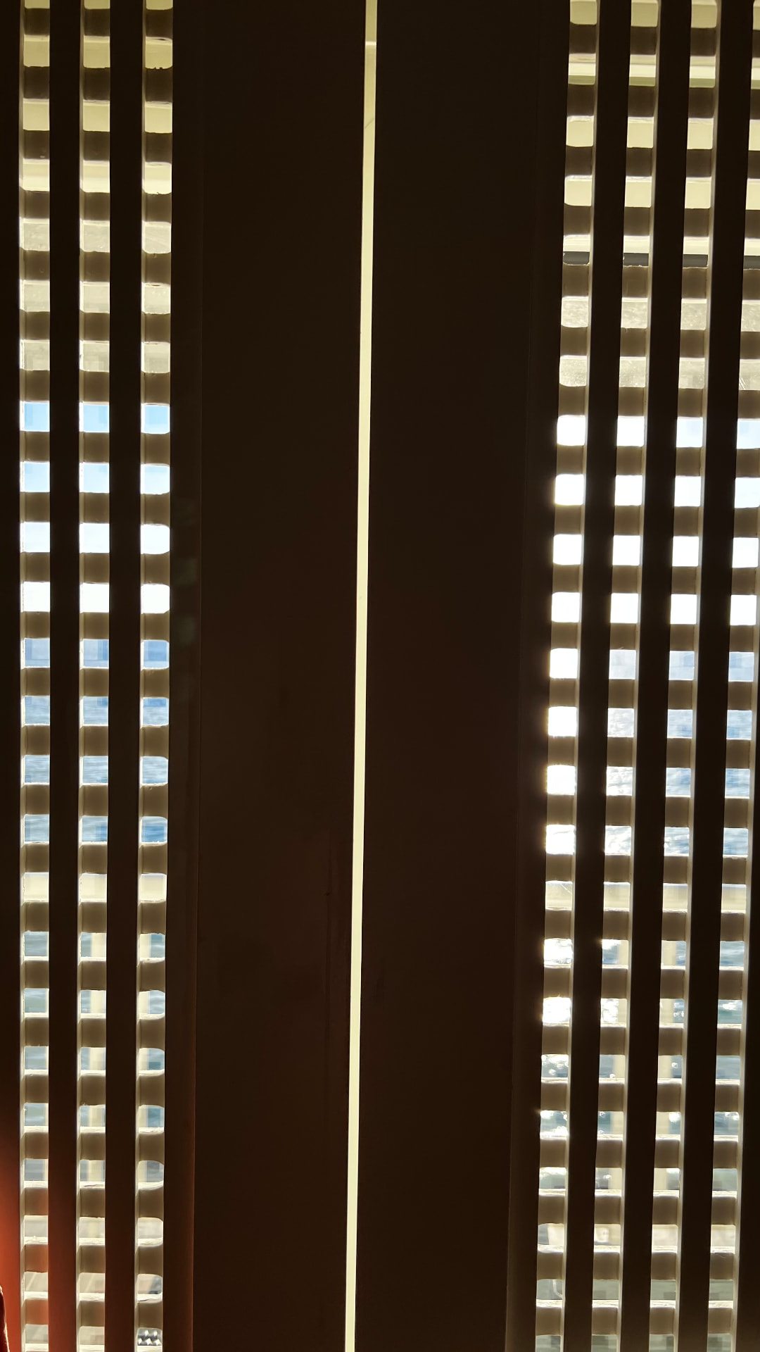 Sunlight and ocean glimpsed through geometric wooden screens