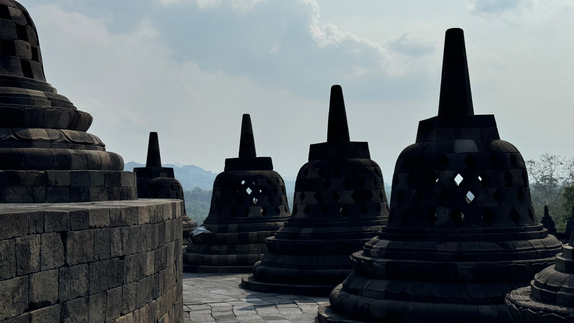 Stupas silhouetted against a bright sky