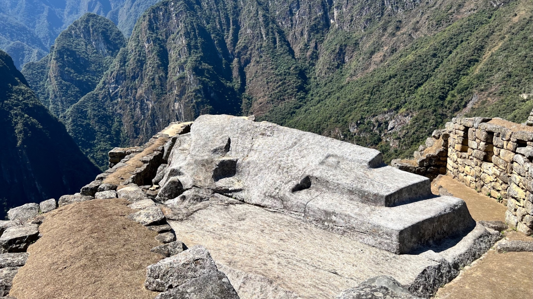 Carved ritual stone on a high terrace overlooking steep forested mountains