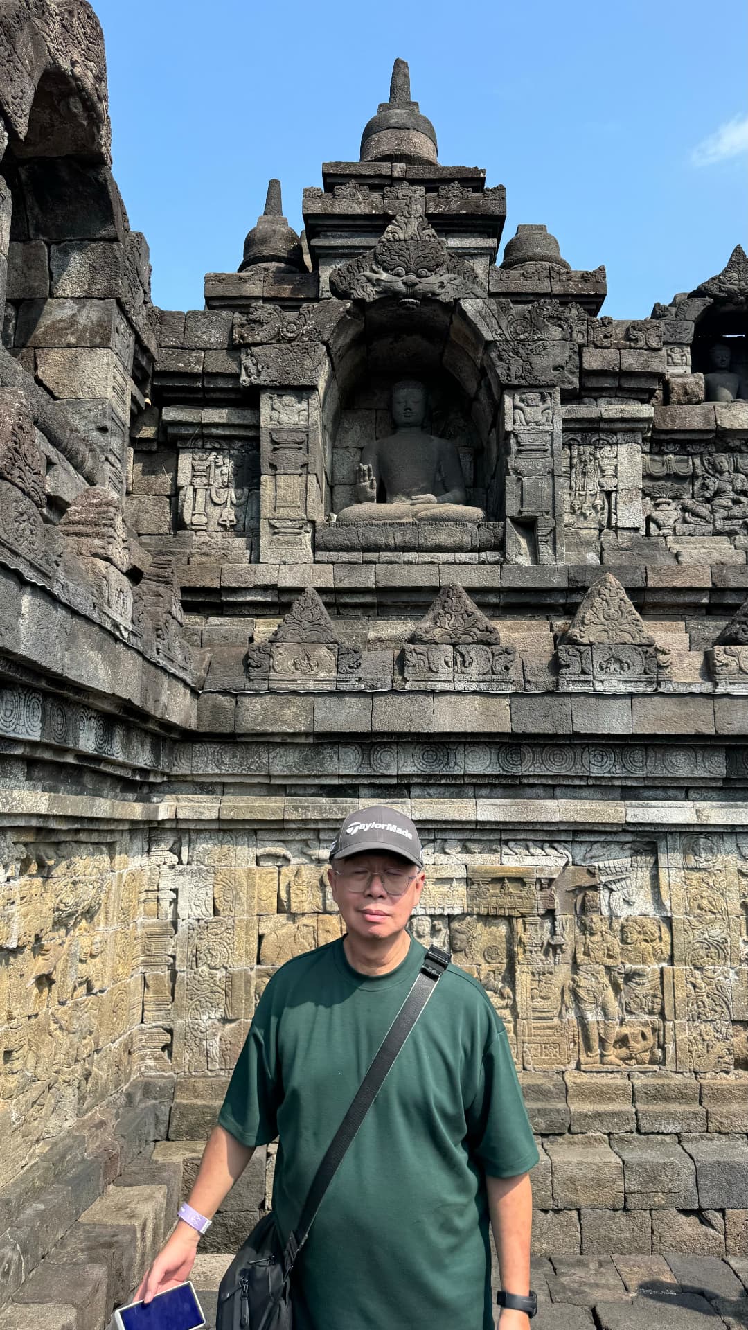 Ken standing below a seated Buddha in a stone niche