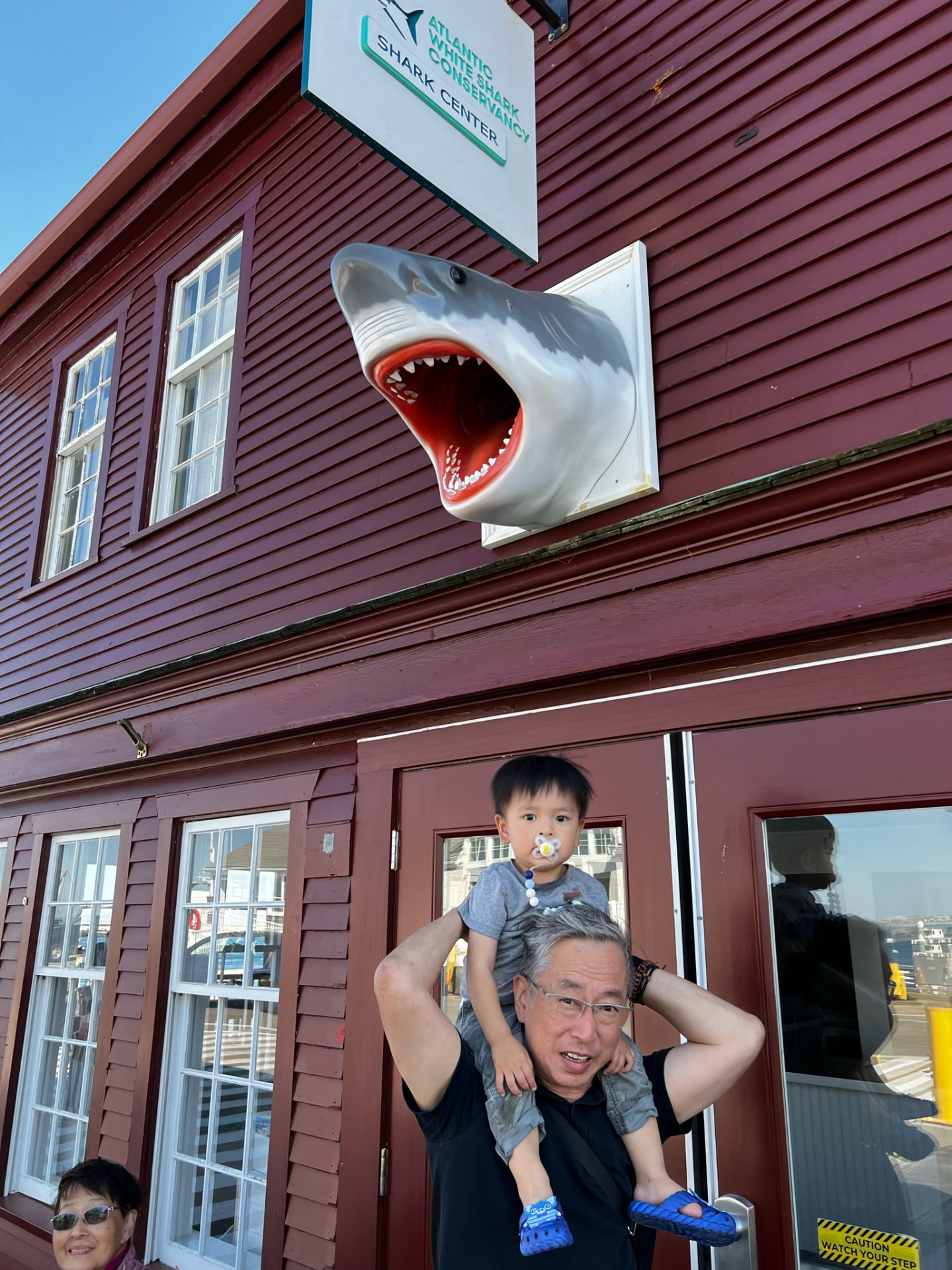 Ken carrying his grandson beneath the Atlantic White Shark Conservancy sign