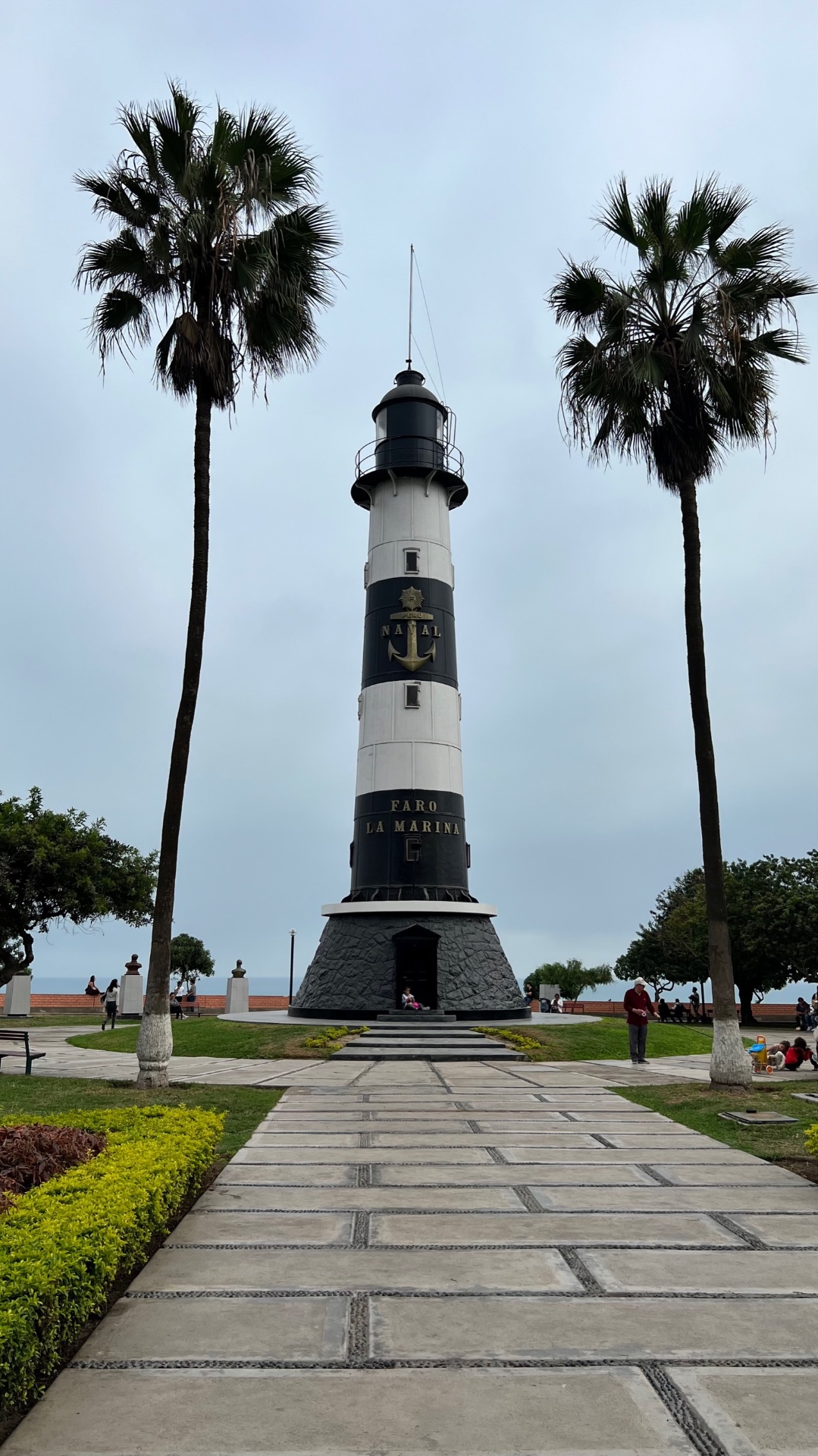 Faro La Marina lighthouse framed by two tall palm trees in Lima