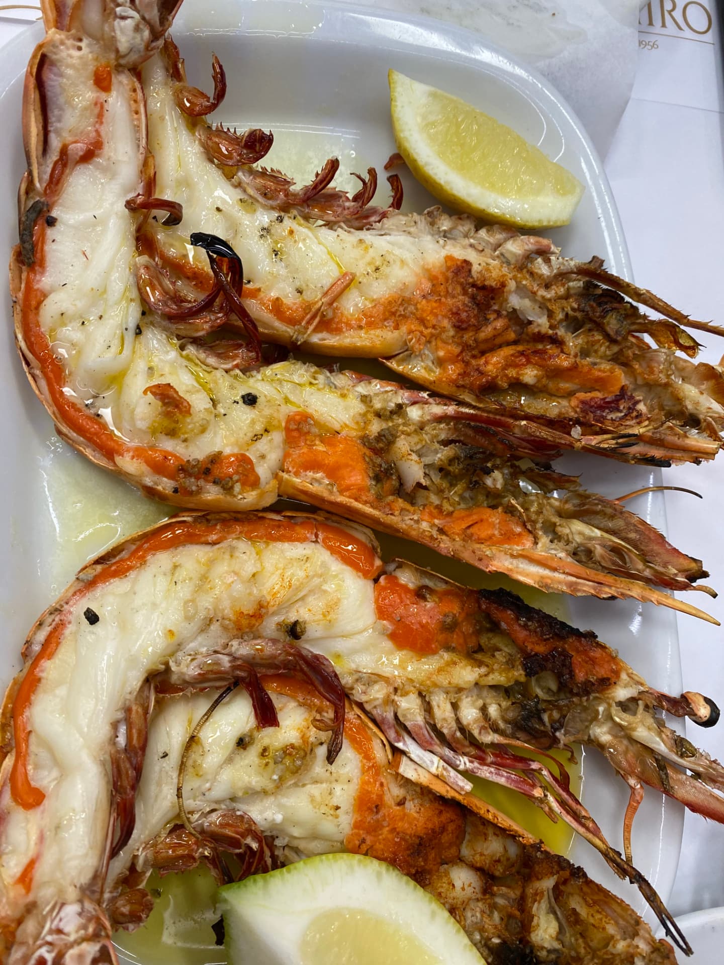 Grilled tiger prawns with lemon on a white plate
