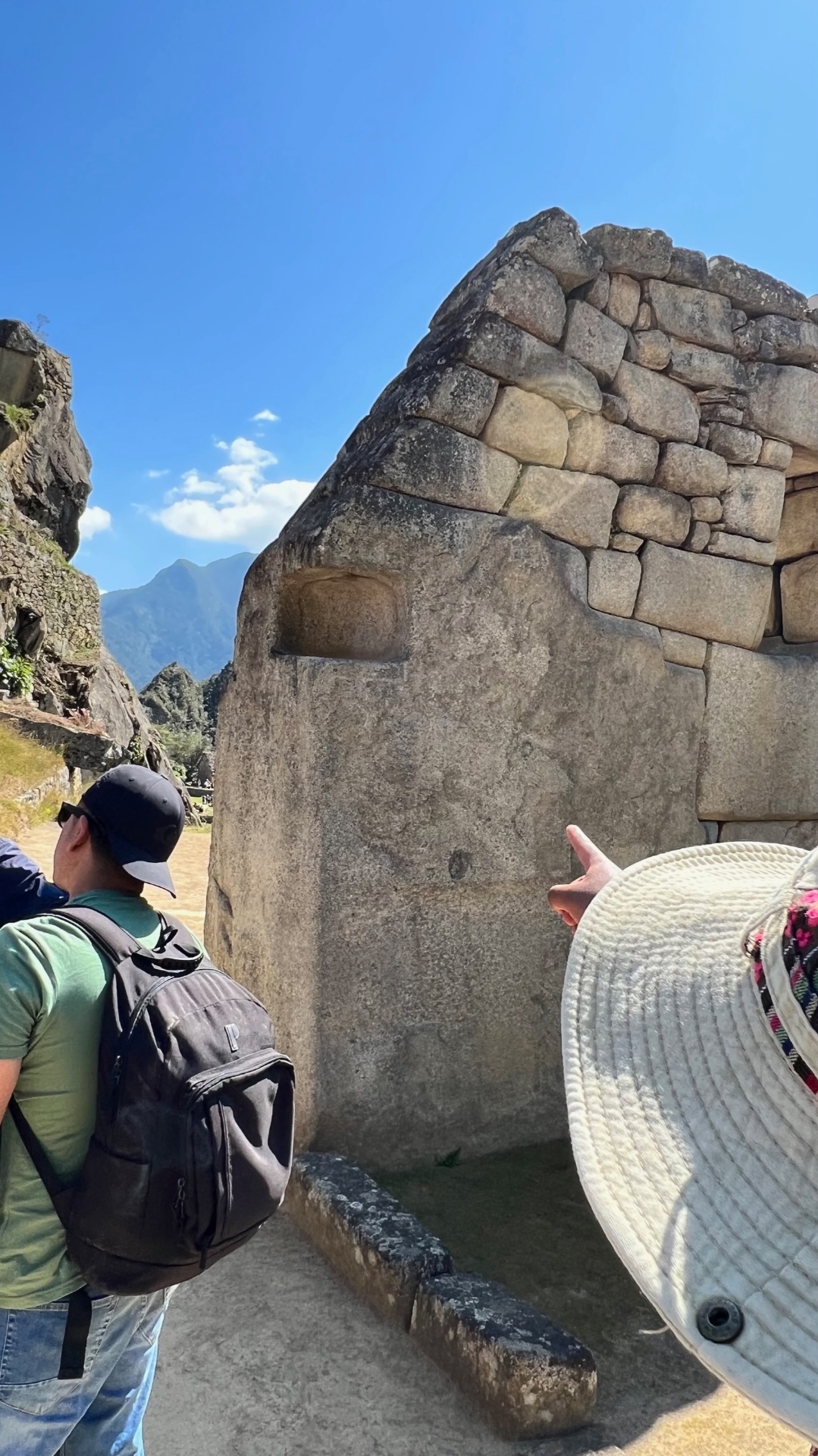 Guide pointing out a finely fitted carved stone wall at Machu Picchu