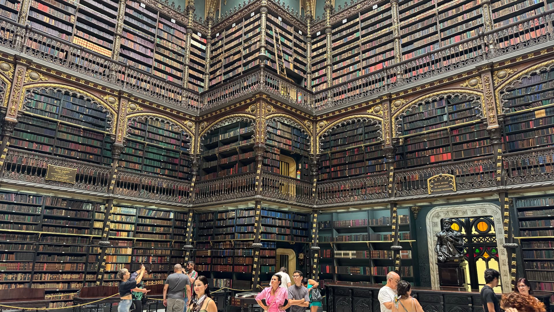 Grand reading room surrounded by floor-to-ceiling bookcases and carved galleries