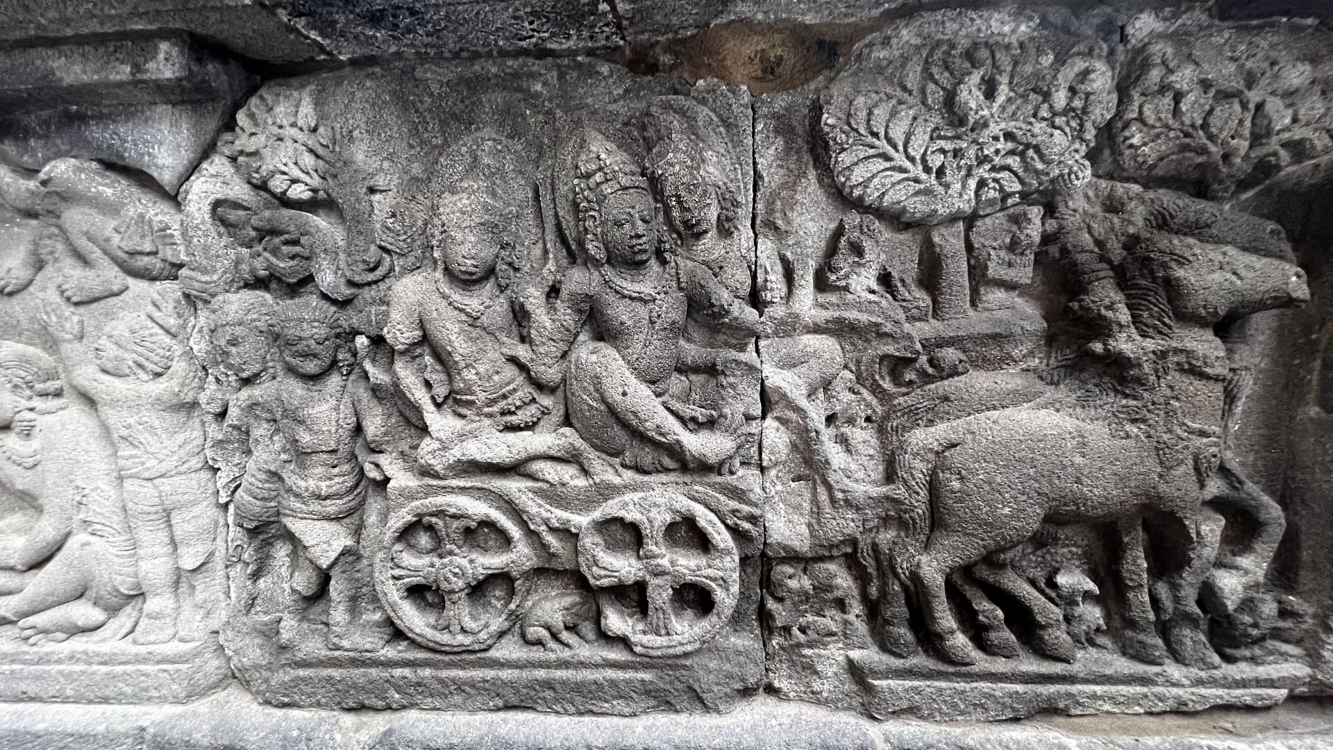 Stone relief of figures and a chariot on a temple wall