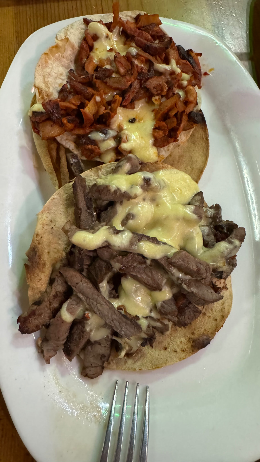 Two generously filled meat tacos topped with melted cheese