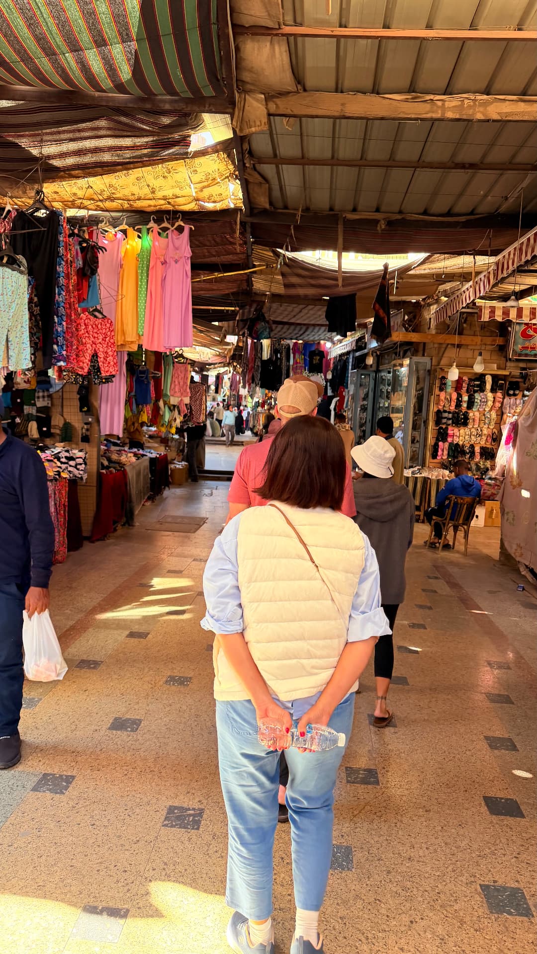 Walking through the covered Aswan bazaar past hanging dresses and shoe displays