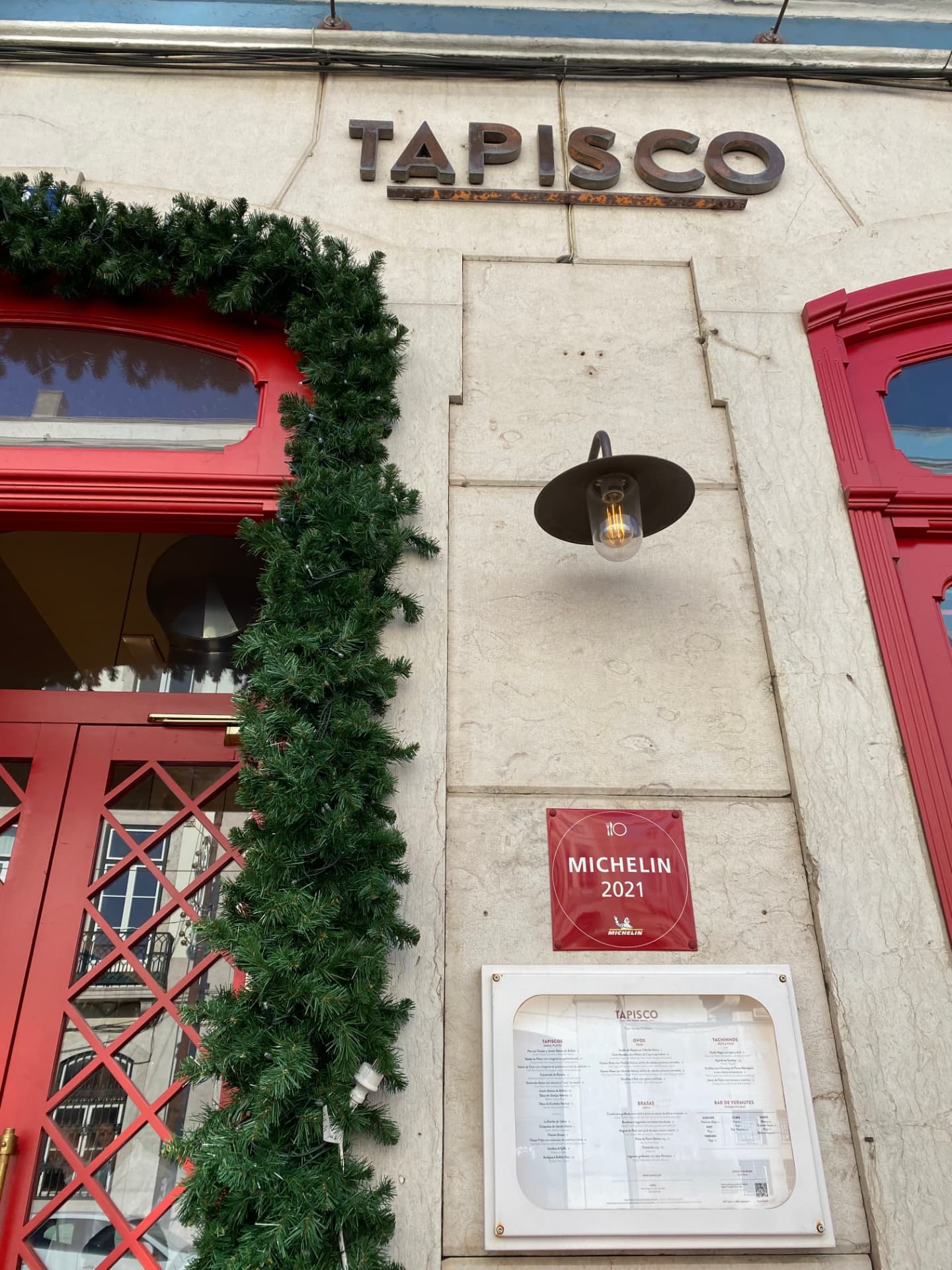 The white front of the Tapisco restaurant with a green garland