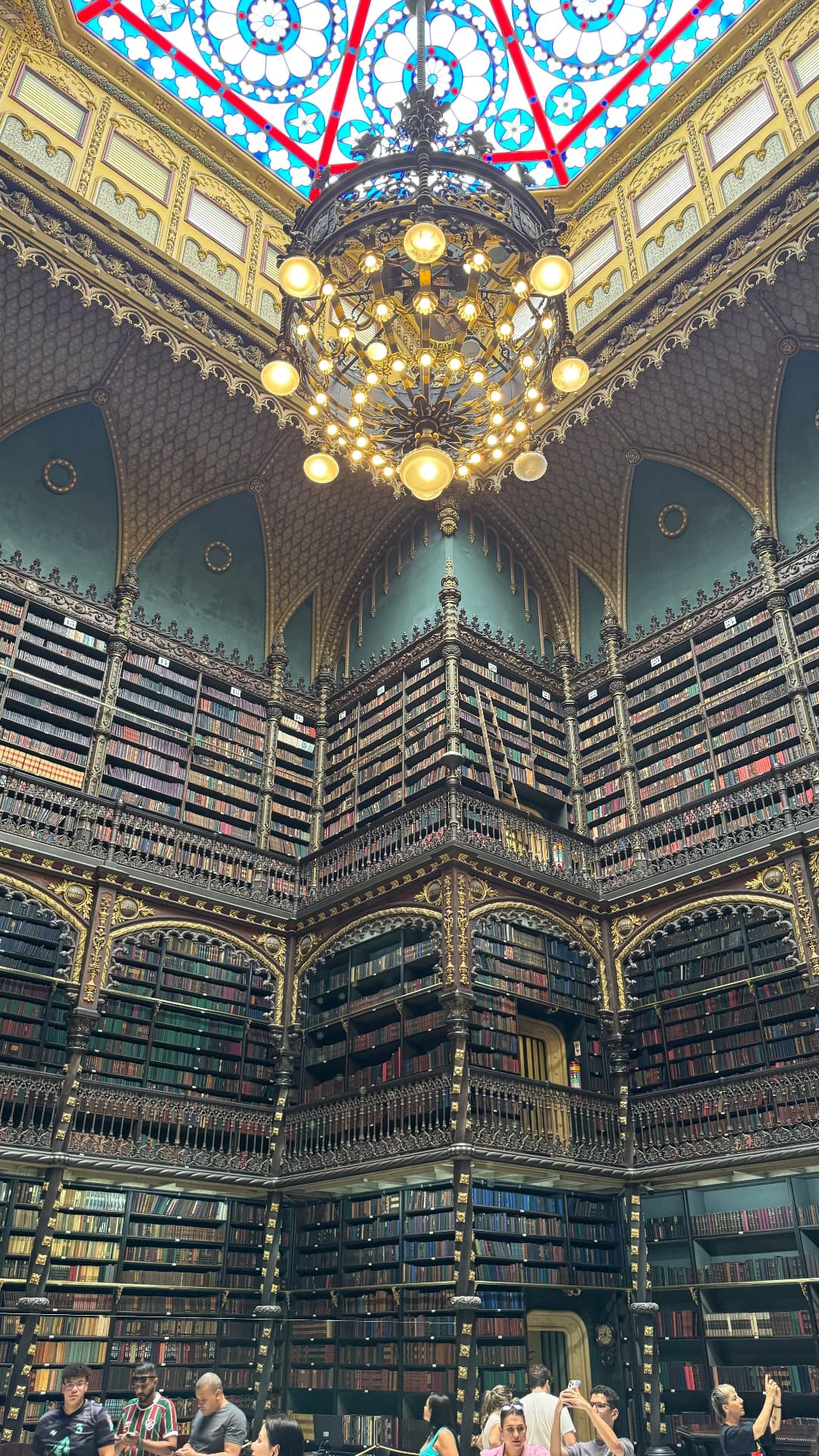 Ornate chandelier hanging above several levels of carved book galleries