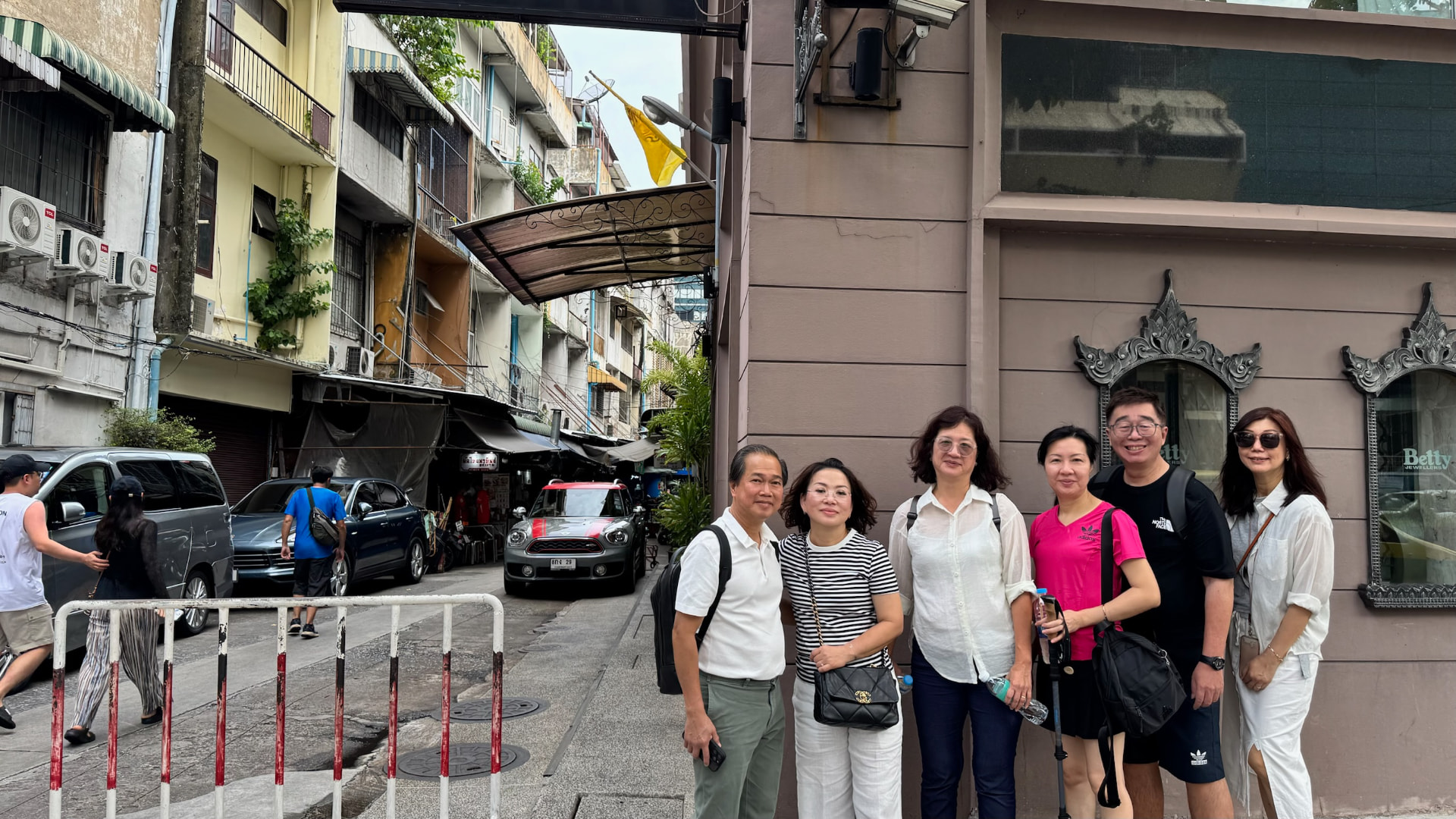 Friends posing together at the entrance to a Bangkok lane