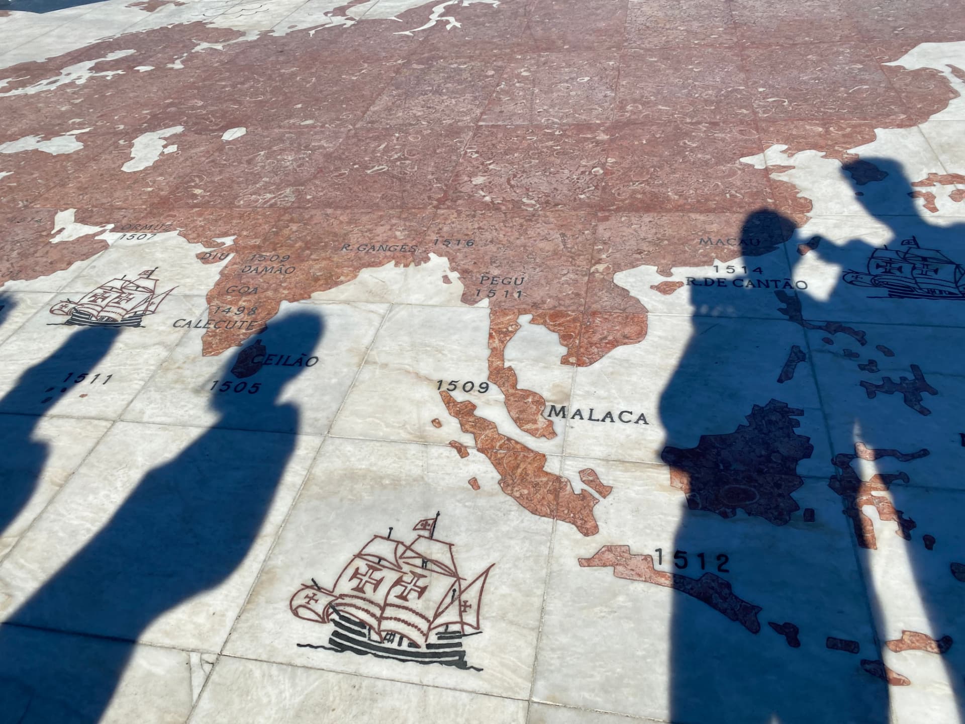 A stone map set into the pavement with visitors' shadows across it