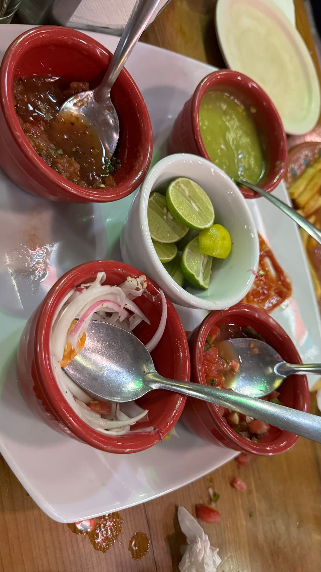 Small bowls of red and green salsa, onions, pico de gallo, and lime