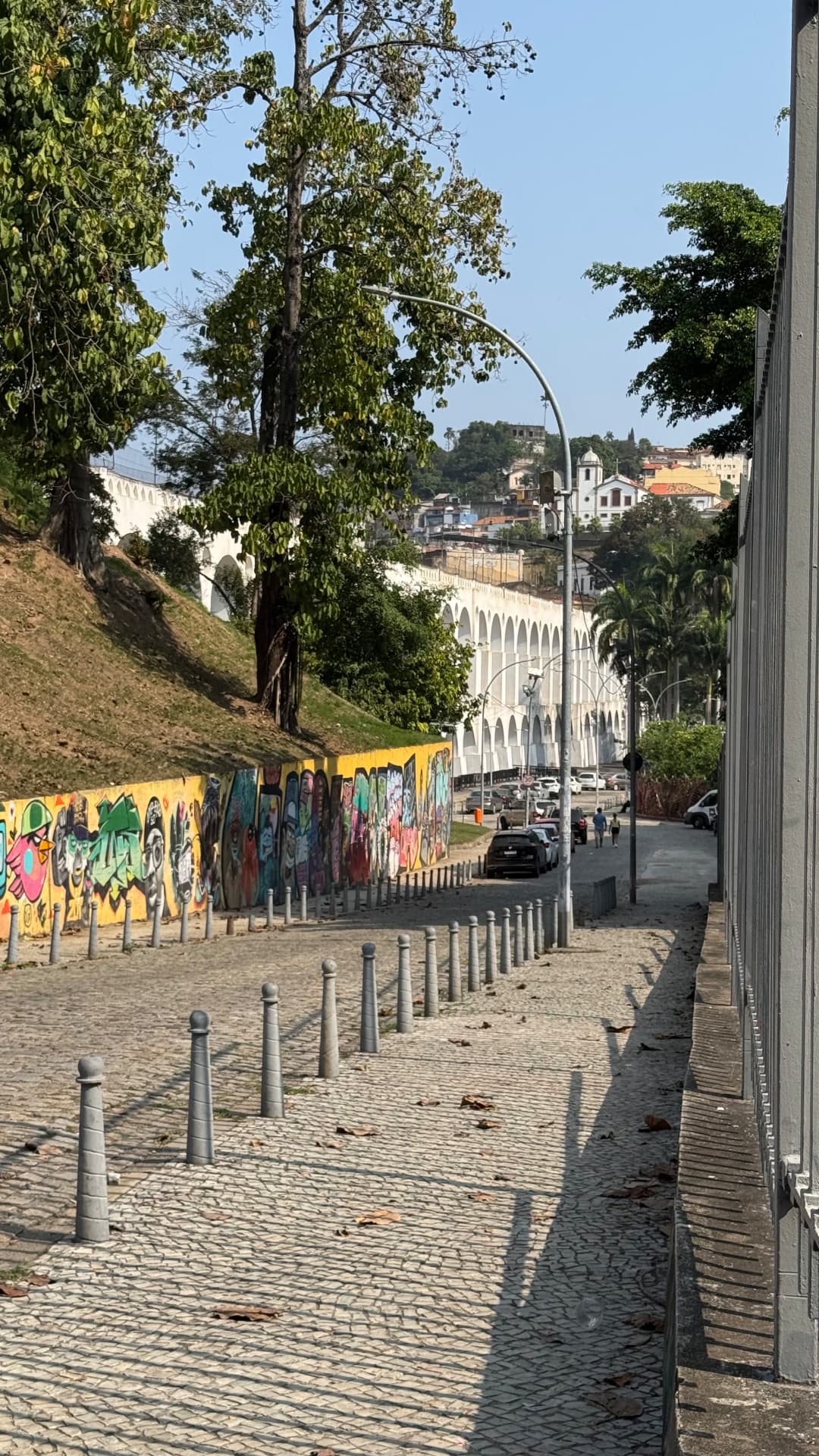 The white arches of the Carioca Aqueduct beyond a cobbled street and painted wall