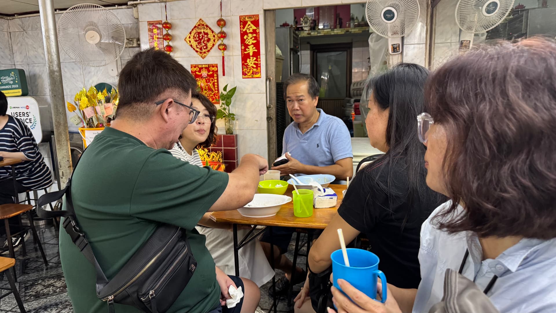 Friends gathered around a table inside a small Bangkok restaurant