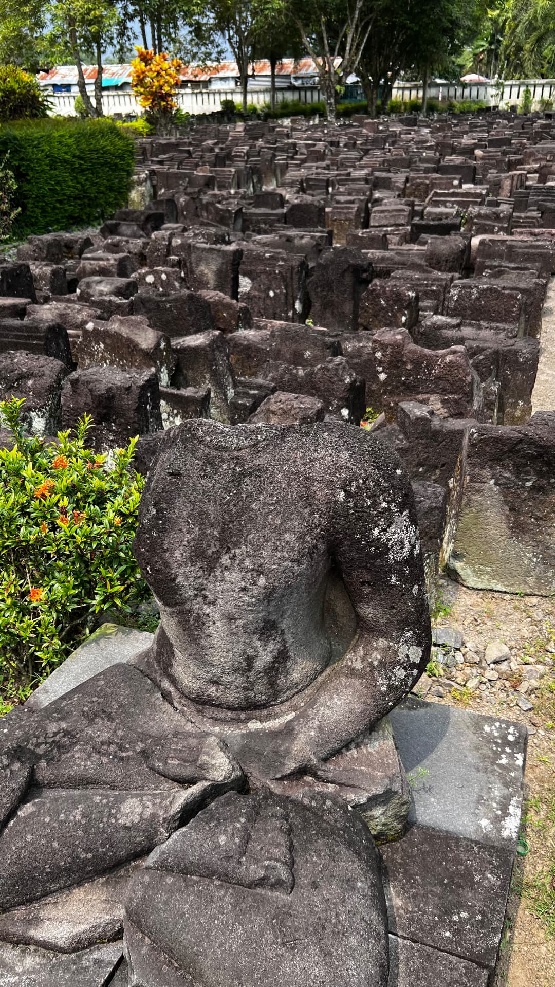 A weathered stone Buddha sculpture near the temple