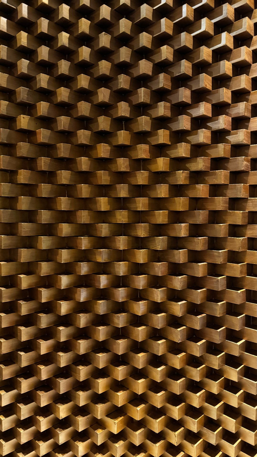 Geometric wall of projecting wooden blocks glowing in warm light