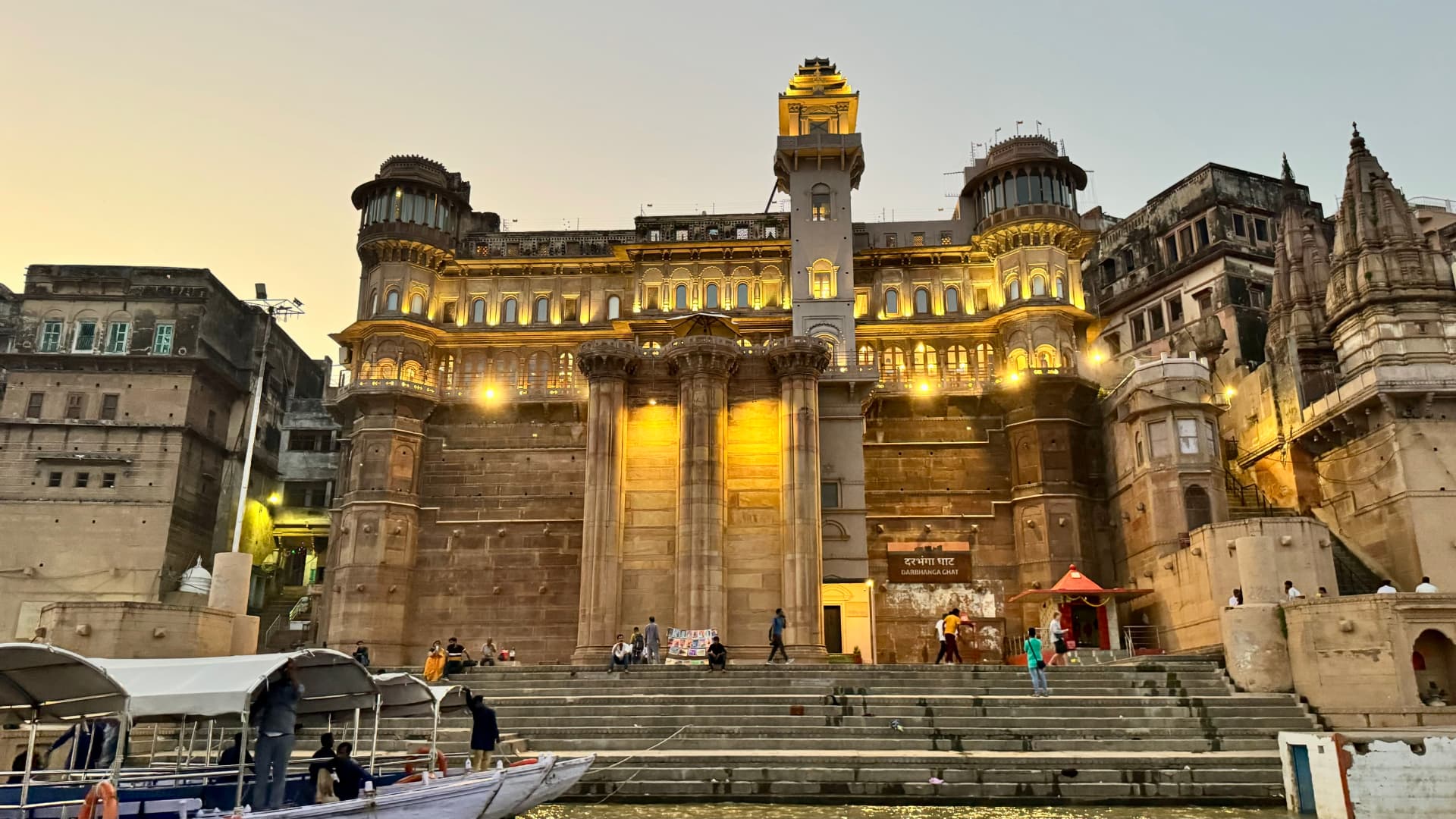 A grand waterfront façade glows under warm evening lights. — Varanasi, Uttar Pradesh, India.