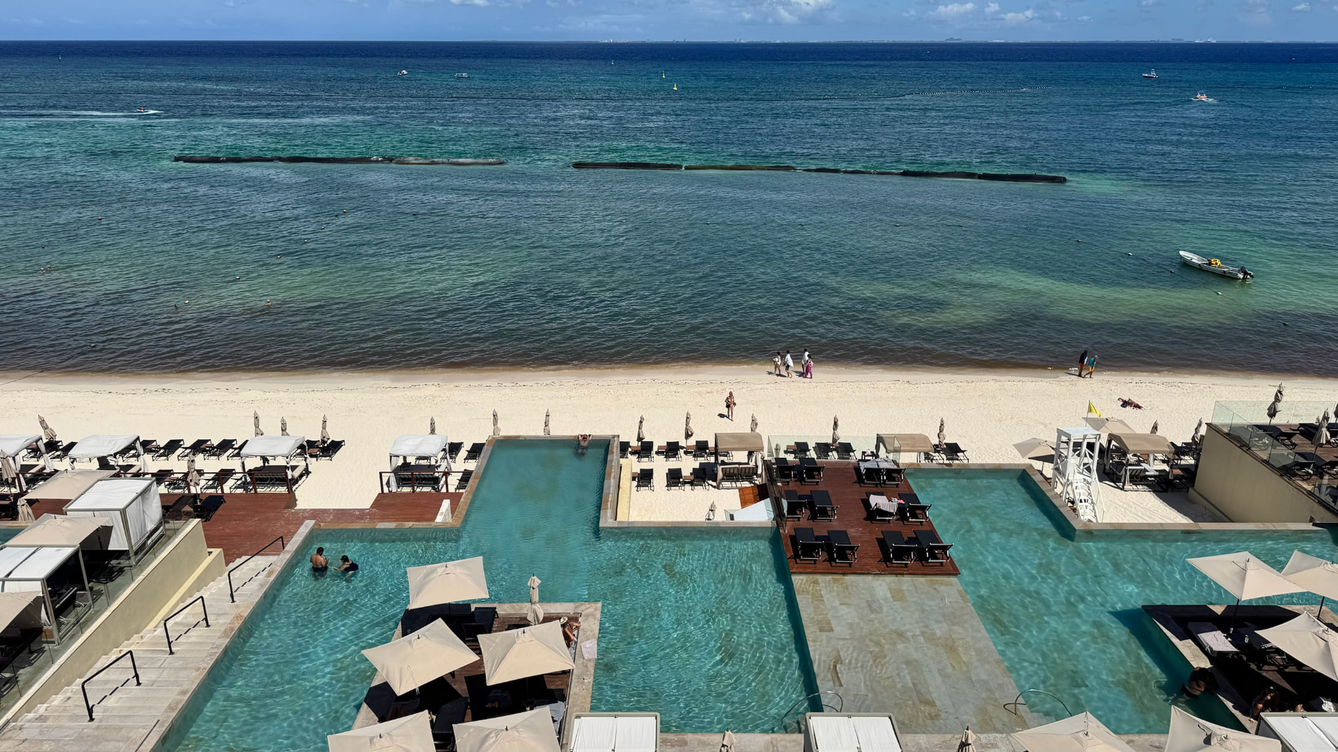 Elevated view over resort pools, white beach, and turquoise sea