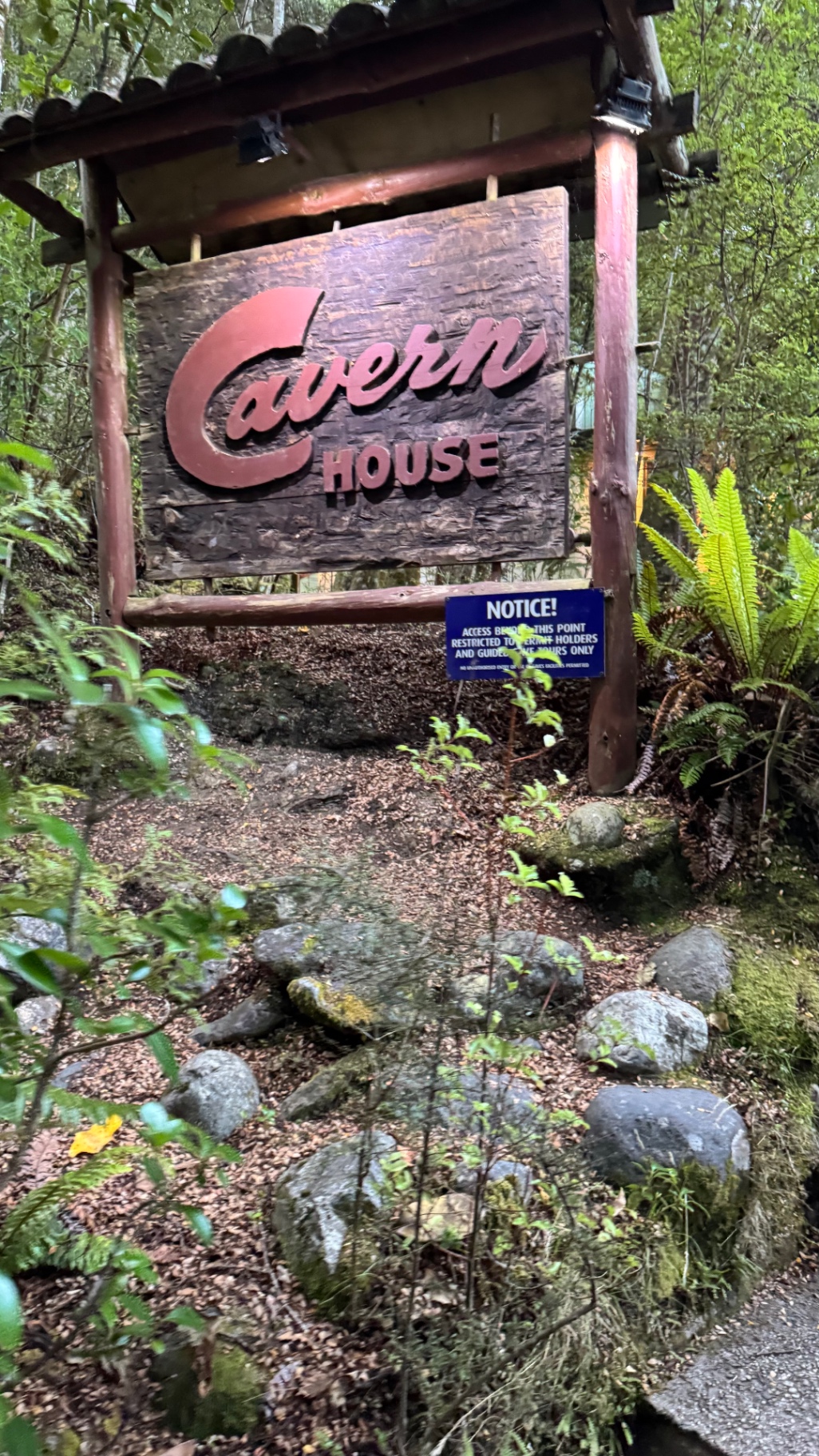 A wooden Cavern House sign at the entrance to the Te Anau Glowworm Cave