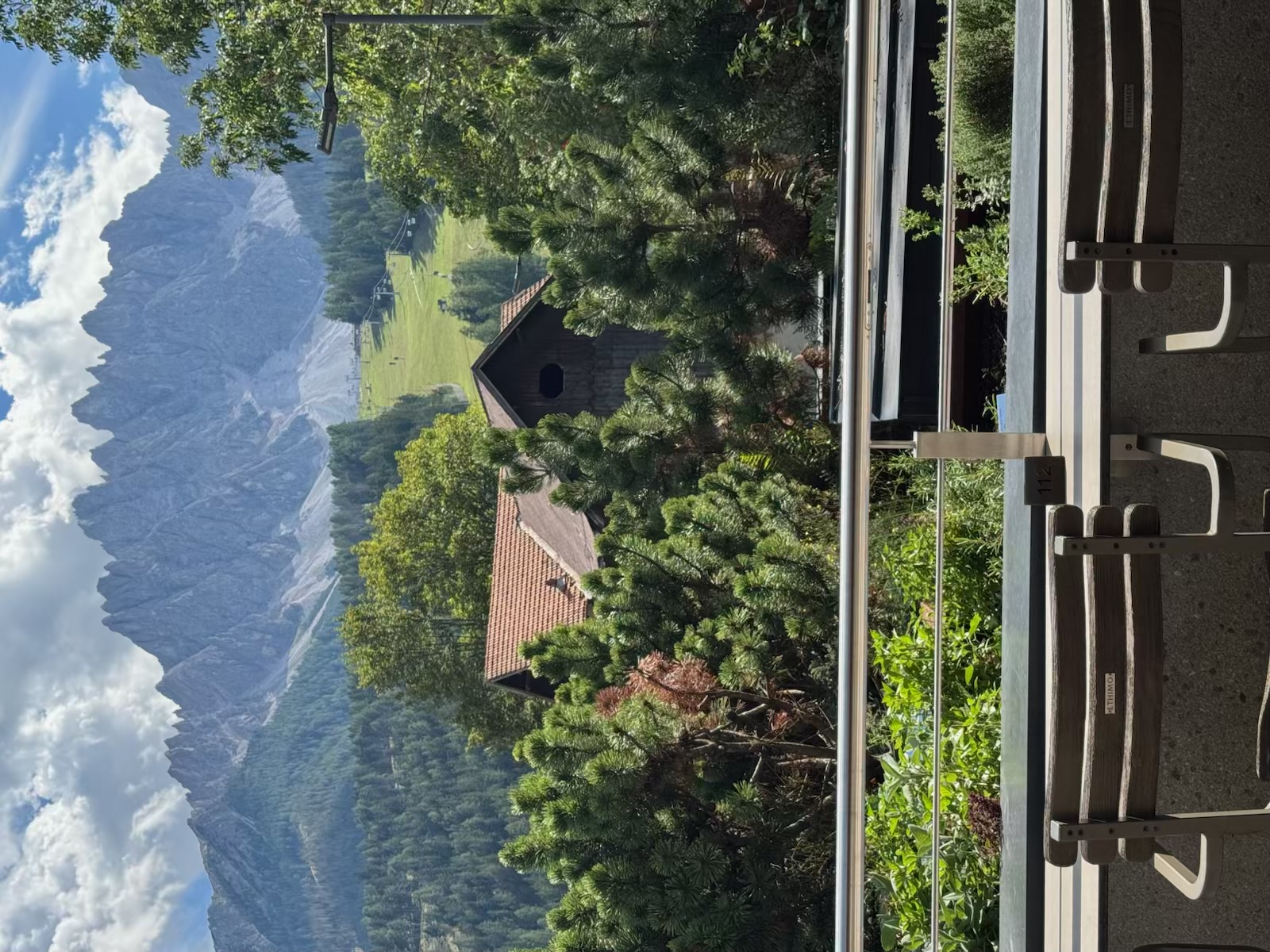A jagged Dolomites ridge rising behind chalet roofs and pine trees