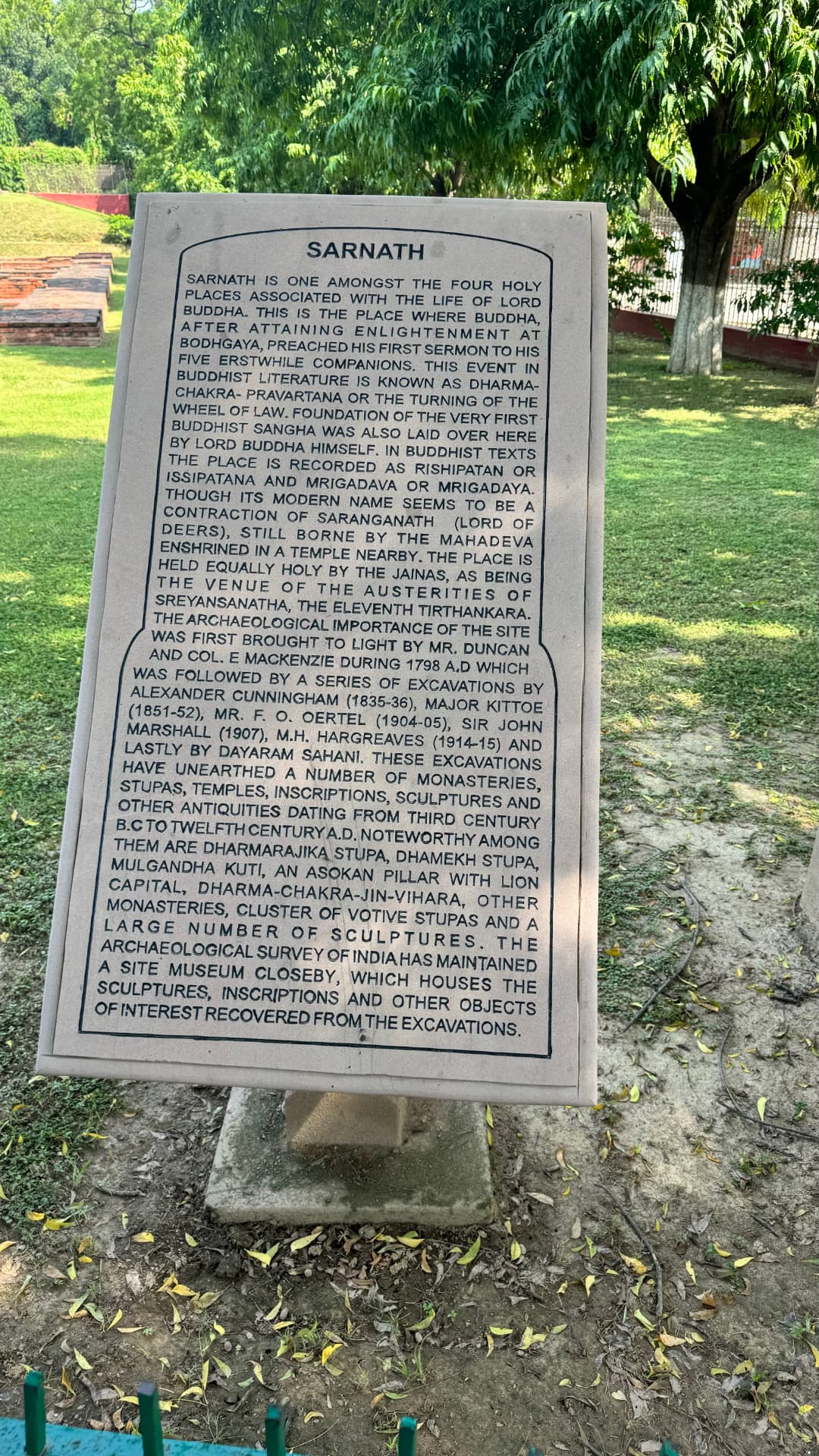 A Sarnath information plaque recounts the site’s Buddhist significance. — Sarnath, Uttar Pradesh, India.
