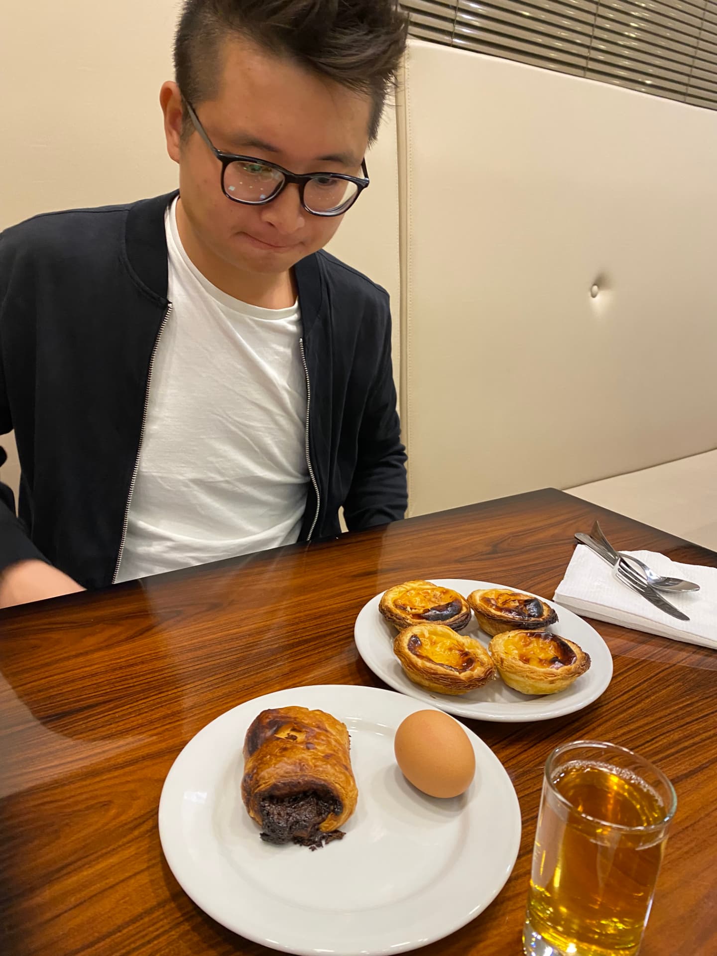 A man seated at a table with pastries and a glass of juice