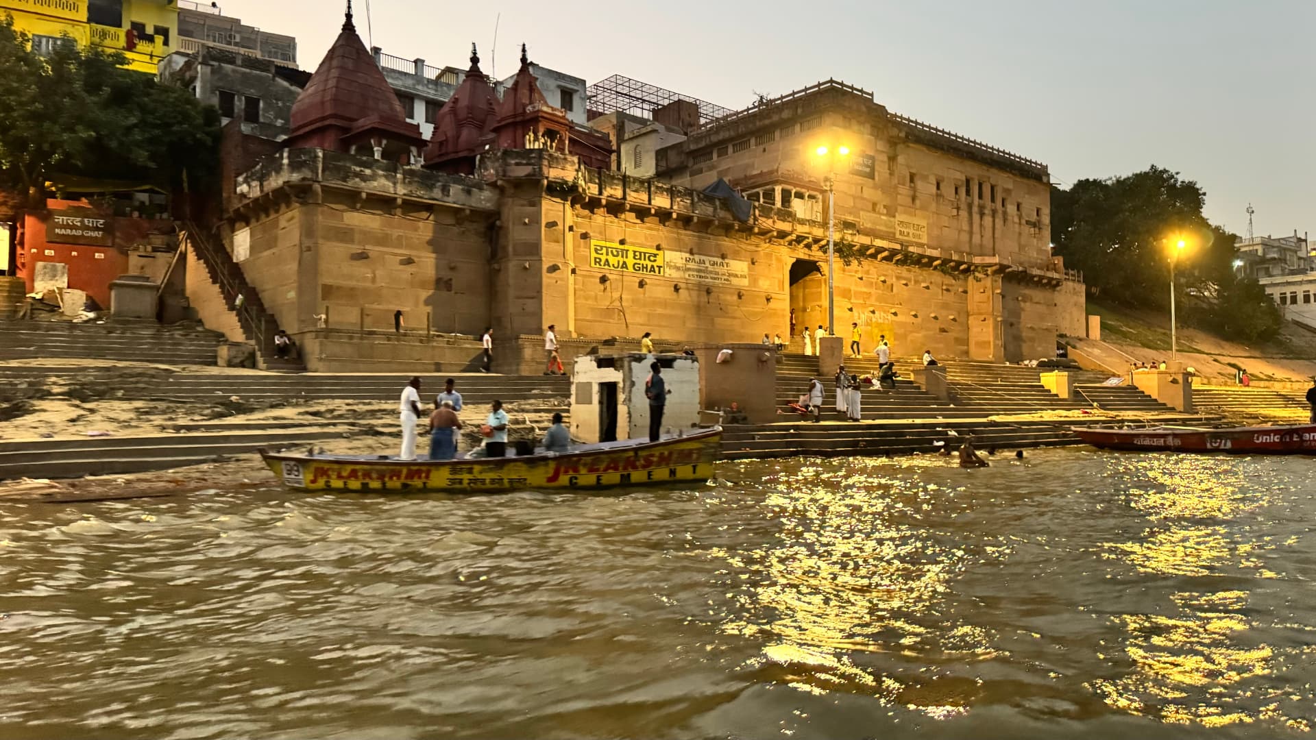 The riverbank lit up after sunset, seen from the water. — Varanasi, Uttar Pradesh, India.