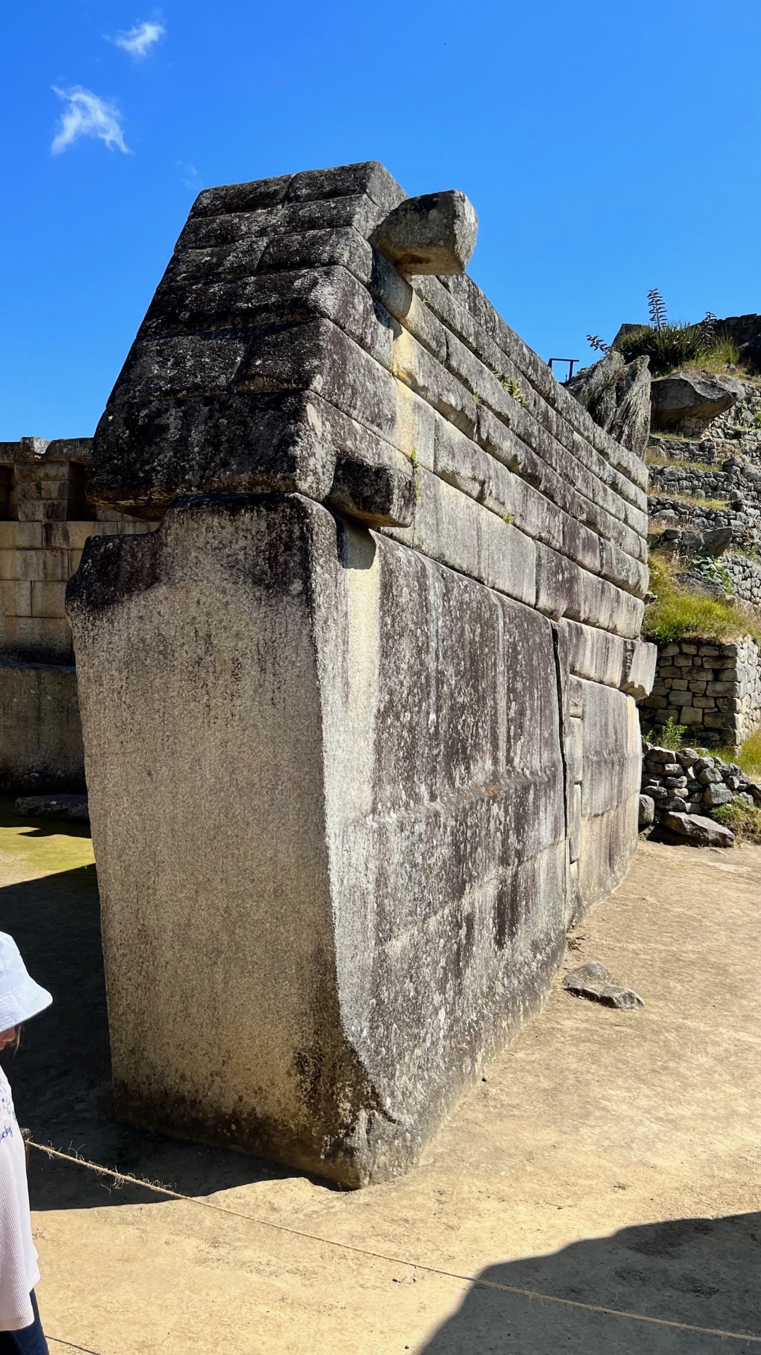 Tall carefully fitted stone wall rising into the blue sky at Machu Picchu