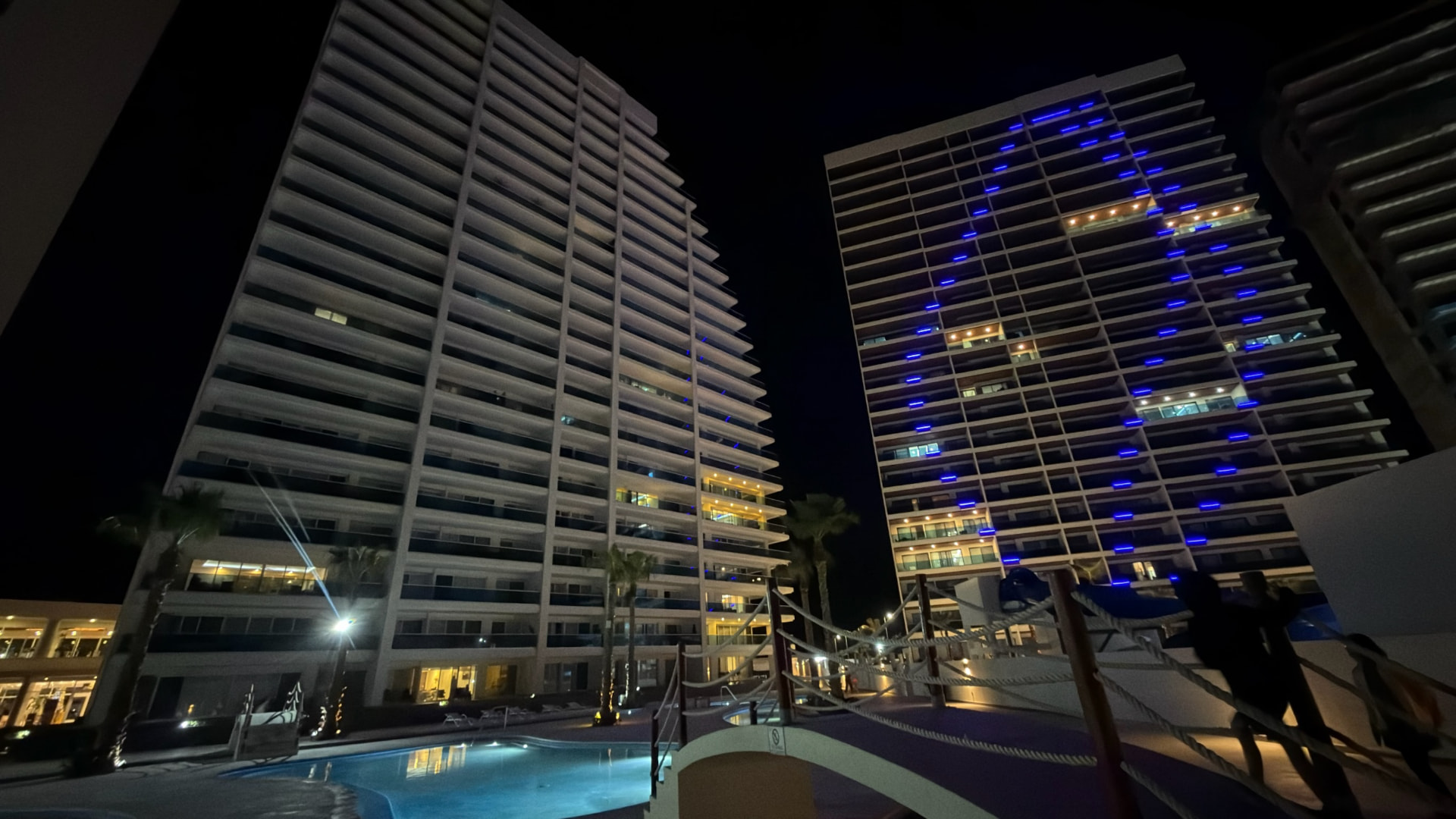 Oceanfront towers and swimming pool illuminated in blue at night