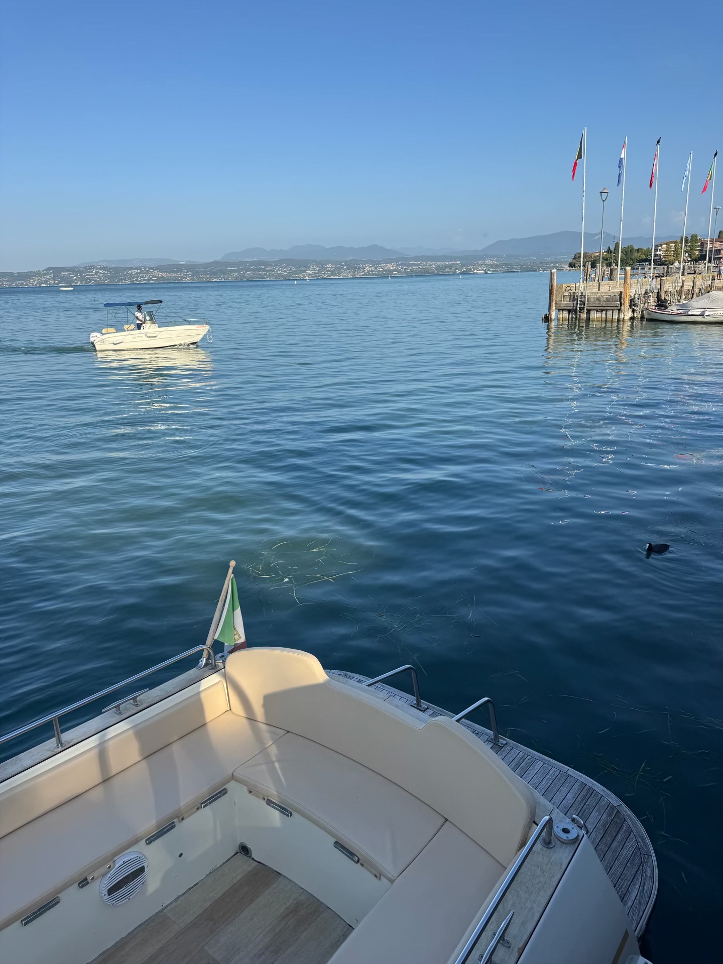 View from a small boat across the calm blue waters of Lake Garda toward Sirmione