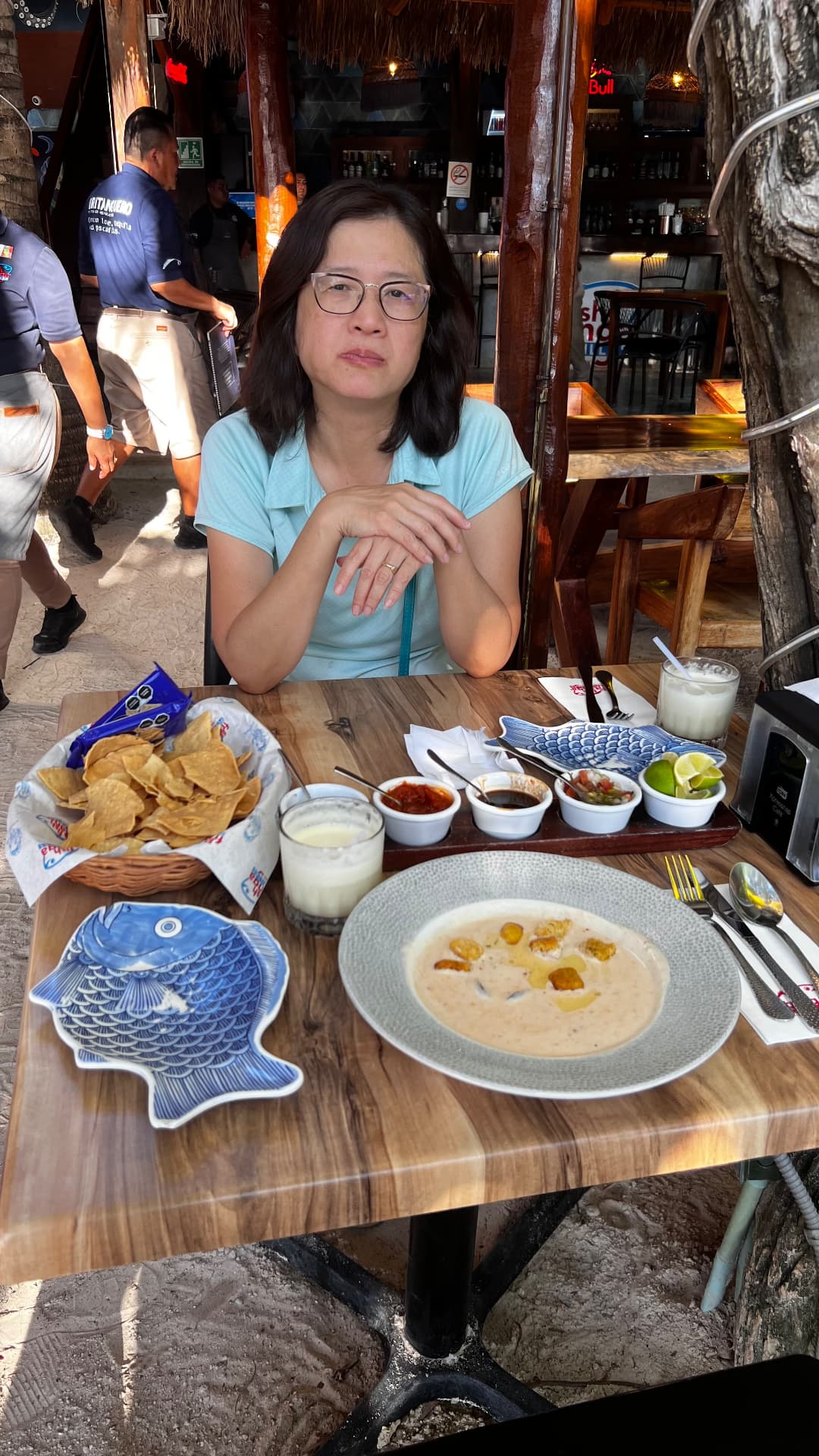 Becky seated at a restaurant table with chowder, chips, and salsas