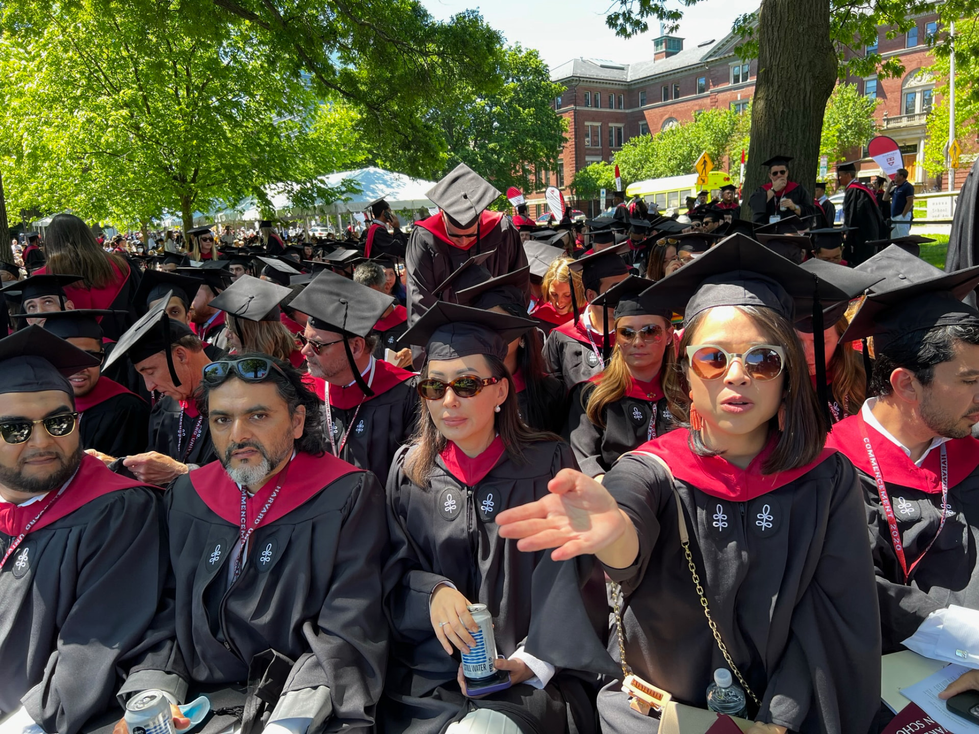 Rows of graduates in black gowns and crimson hoods seated at the ceremony