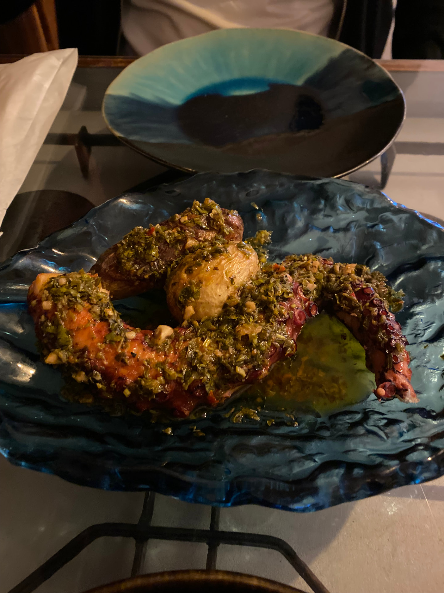A plate of grilled octopus with a green sauce