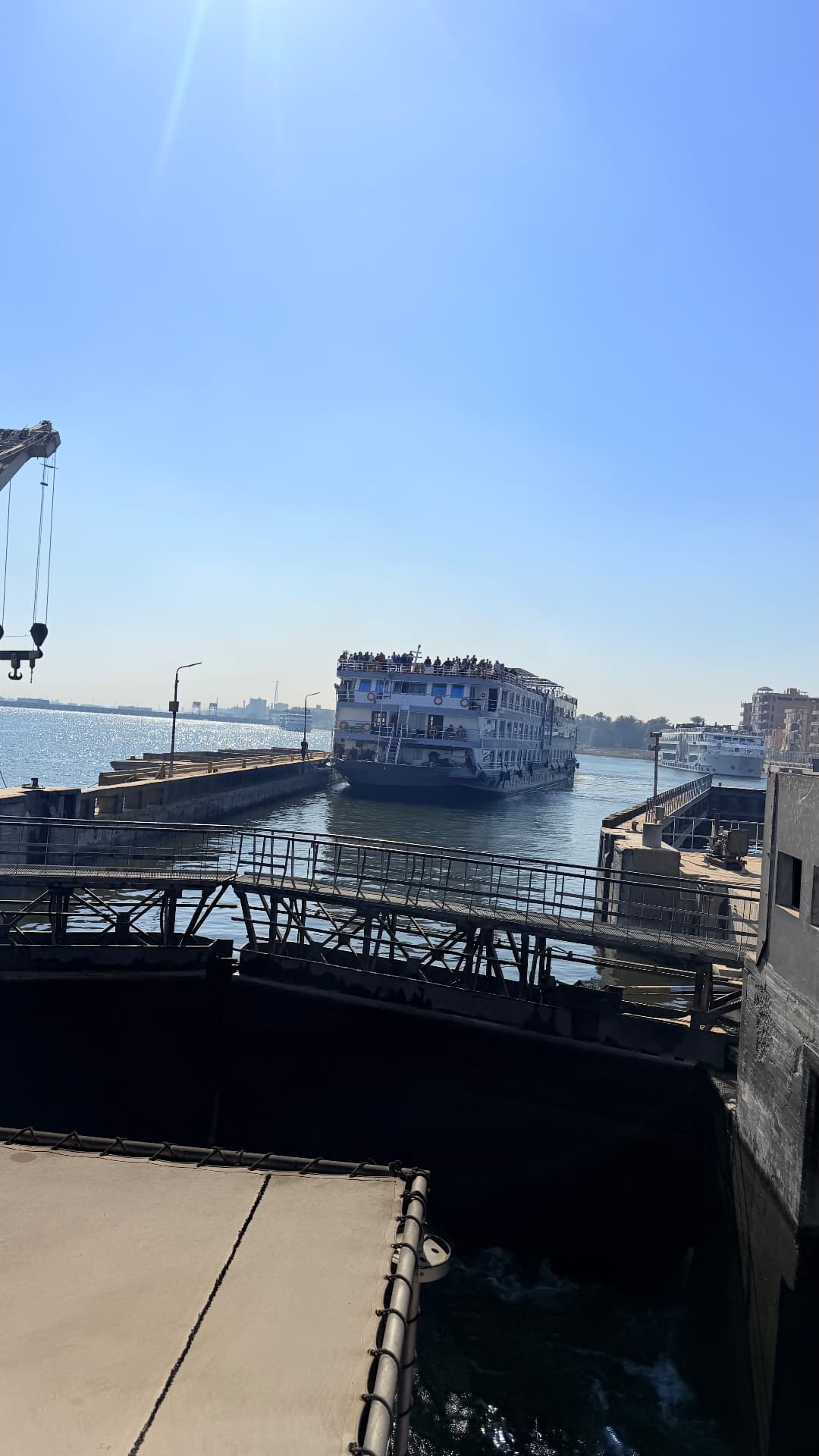 A Nile cruise boat entering the Esna lock chamber with a crane on the wall