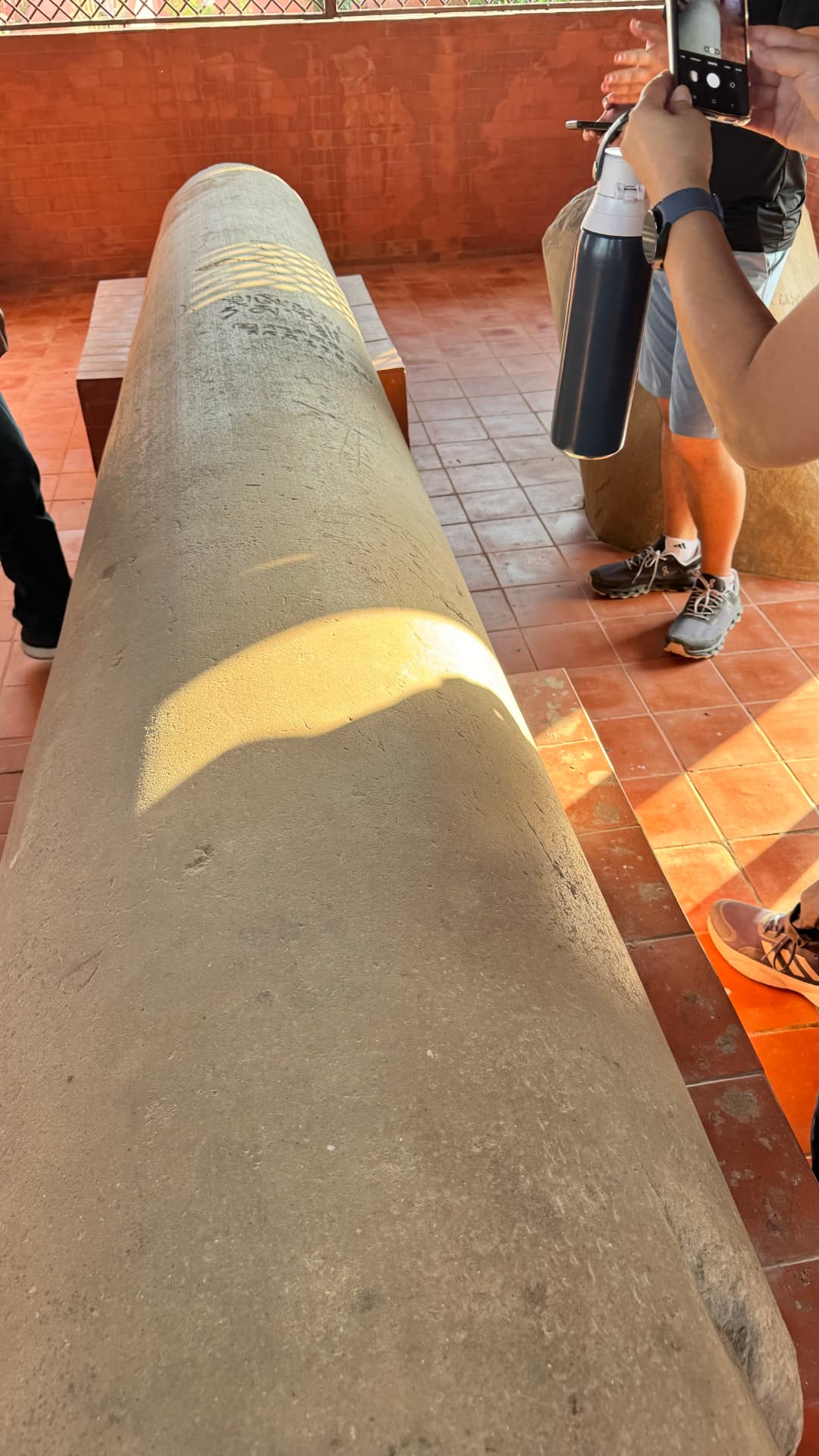 A close view of a stone marker, with visitors gathered beside it. — Lumbini, Nepal.