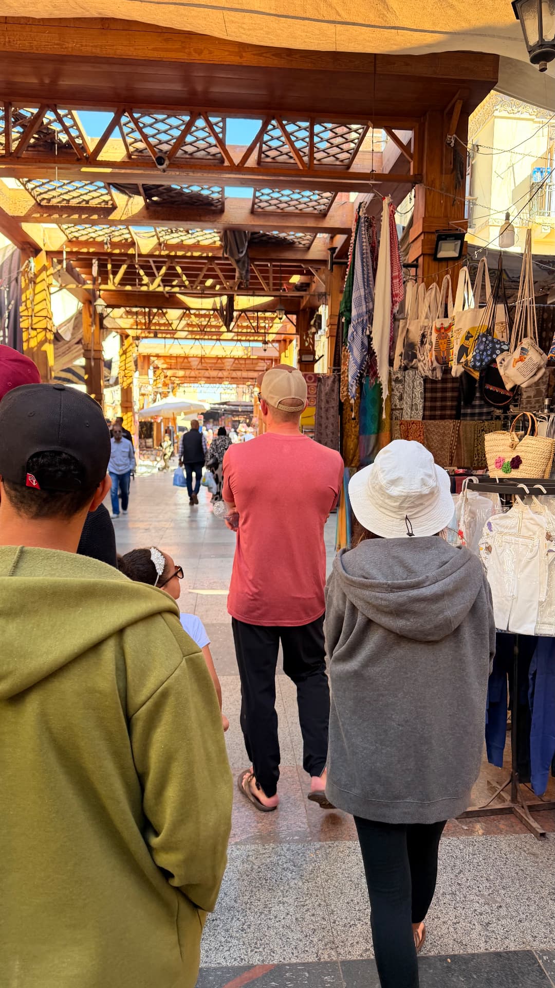 Our group walking under the wooden roof of the Aswan souk past bags and scarves