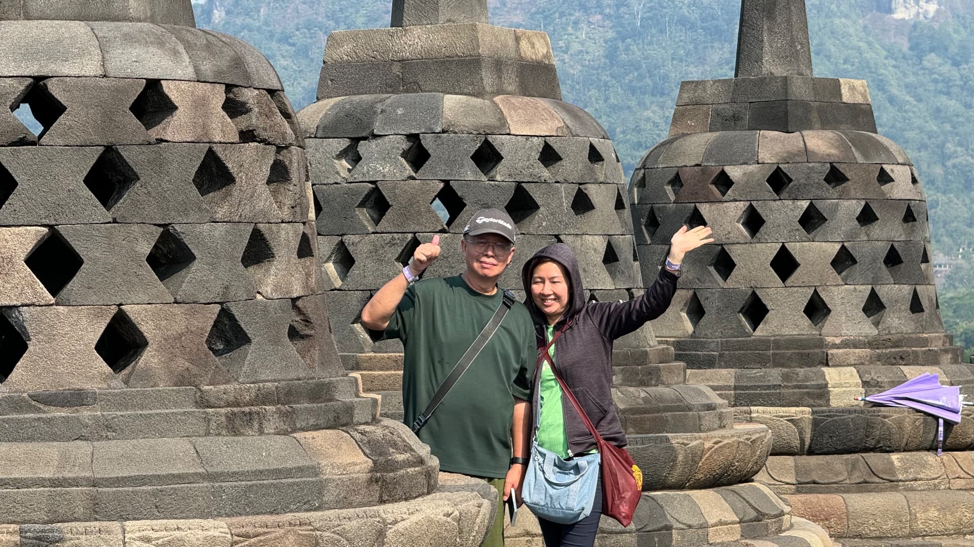 Two travelers smiling among Borobudur's stupas
