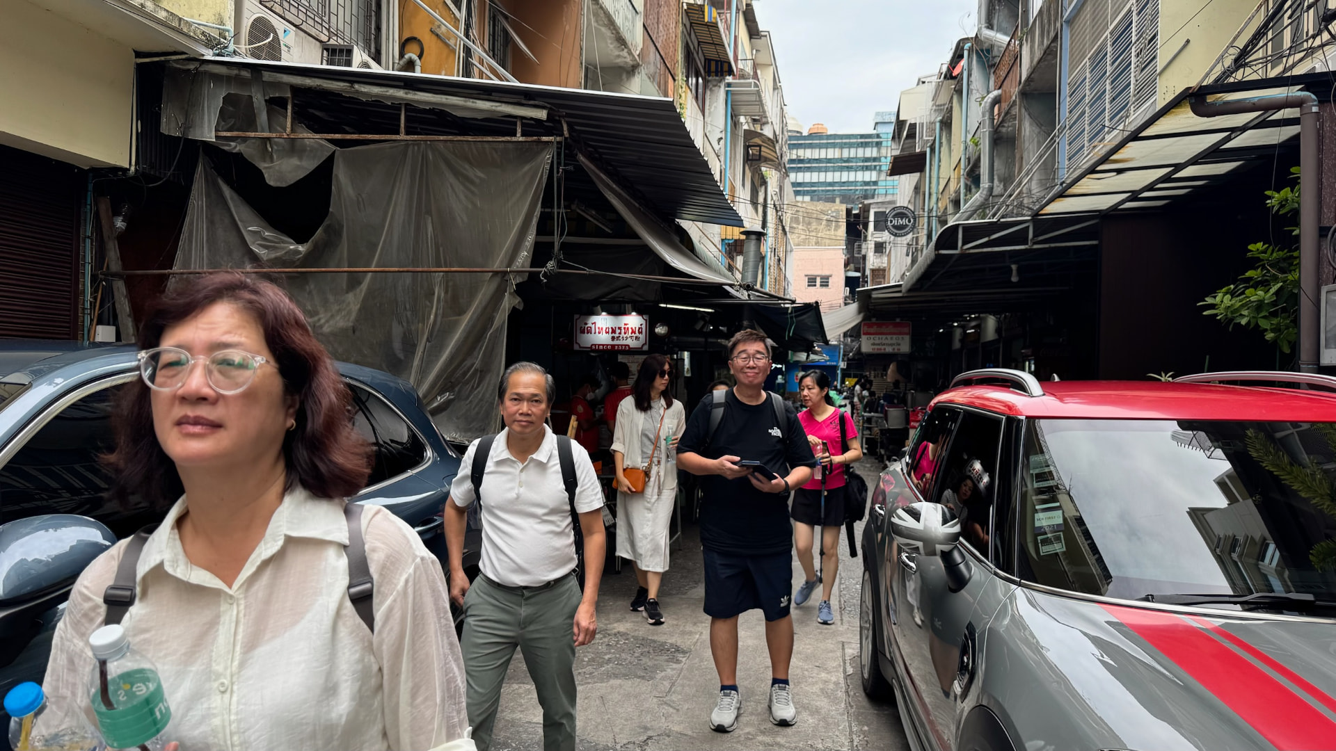 Friends walking through a narrow Bangkok restaurant lane