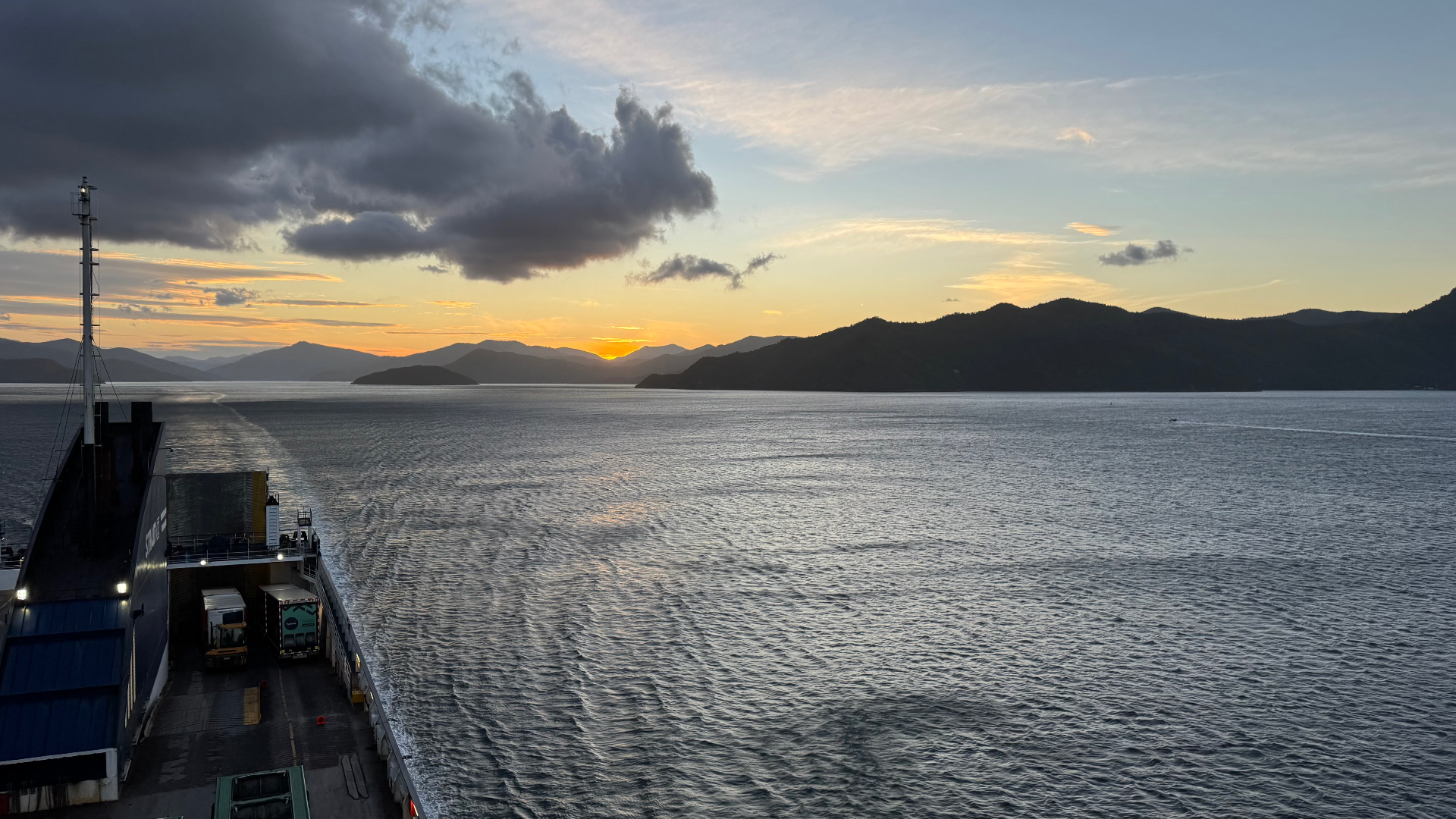 Sunset over the Marlborough Sounds seen from the deck of the Picton ferry, with the ship's wake trailing behind