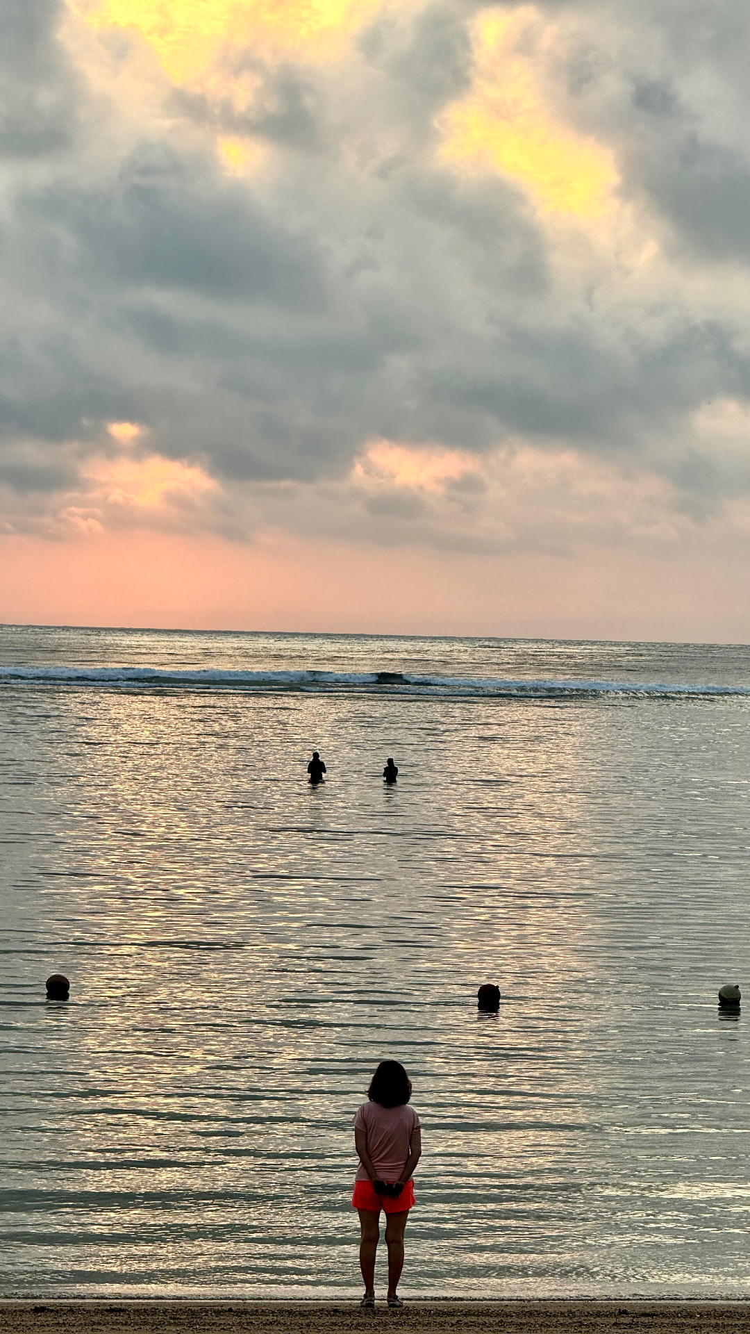 Becky standing at the shoreline beneath a softly glowing sunset sky