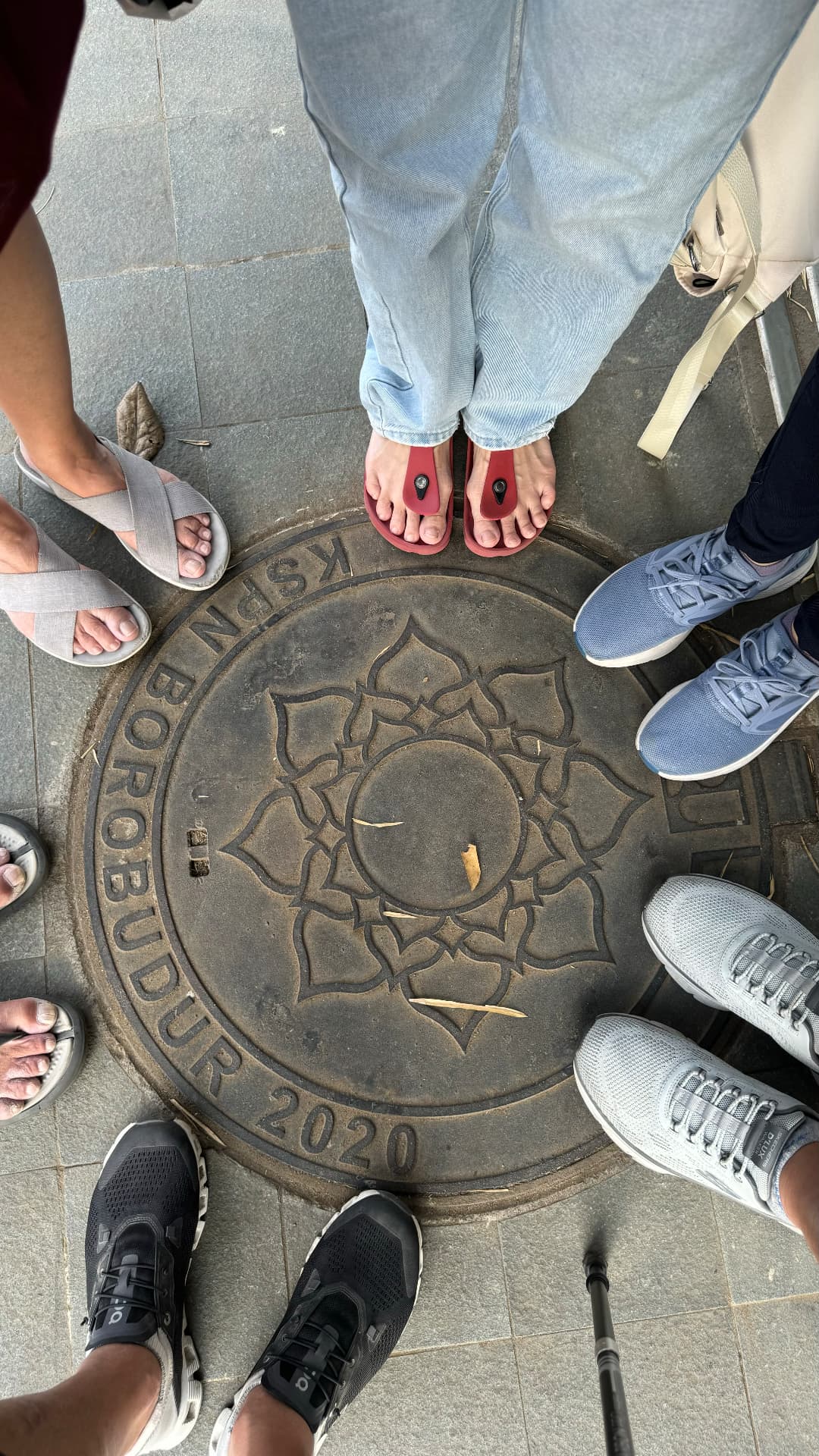 Travelers' shoes circling a Borobudur pavement medallion