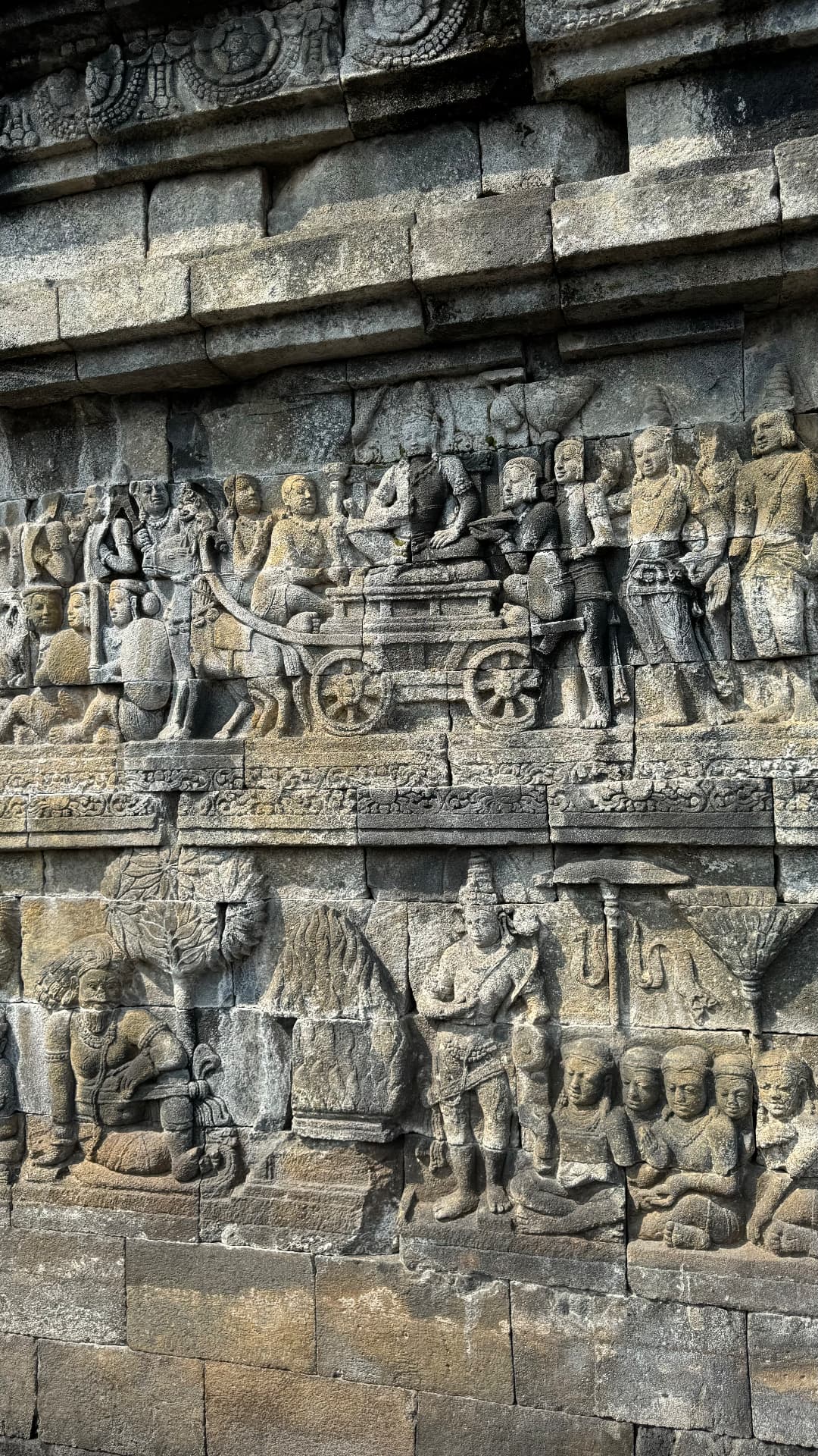 Carved figures and a wheeled cart on the temple wall