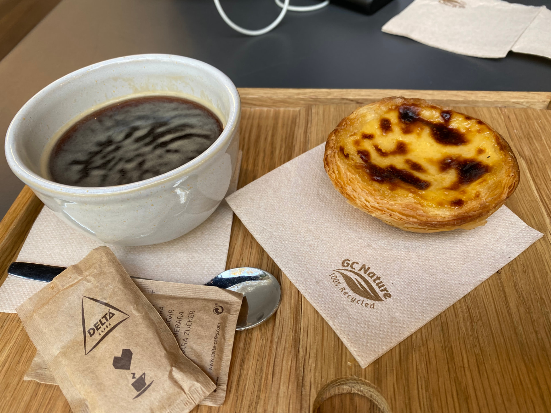 A coffee and a pastel de nata on a small tray